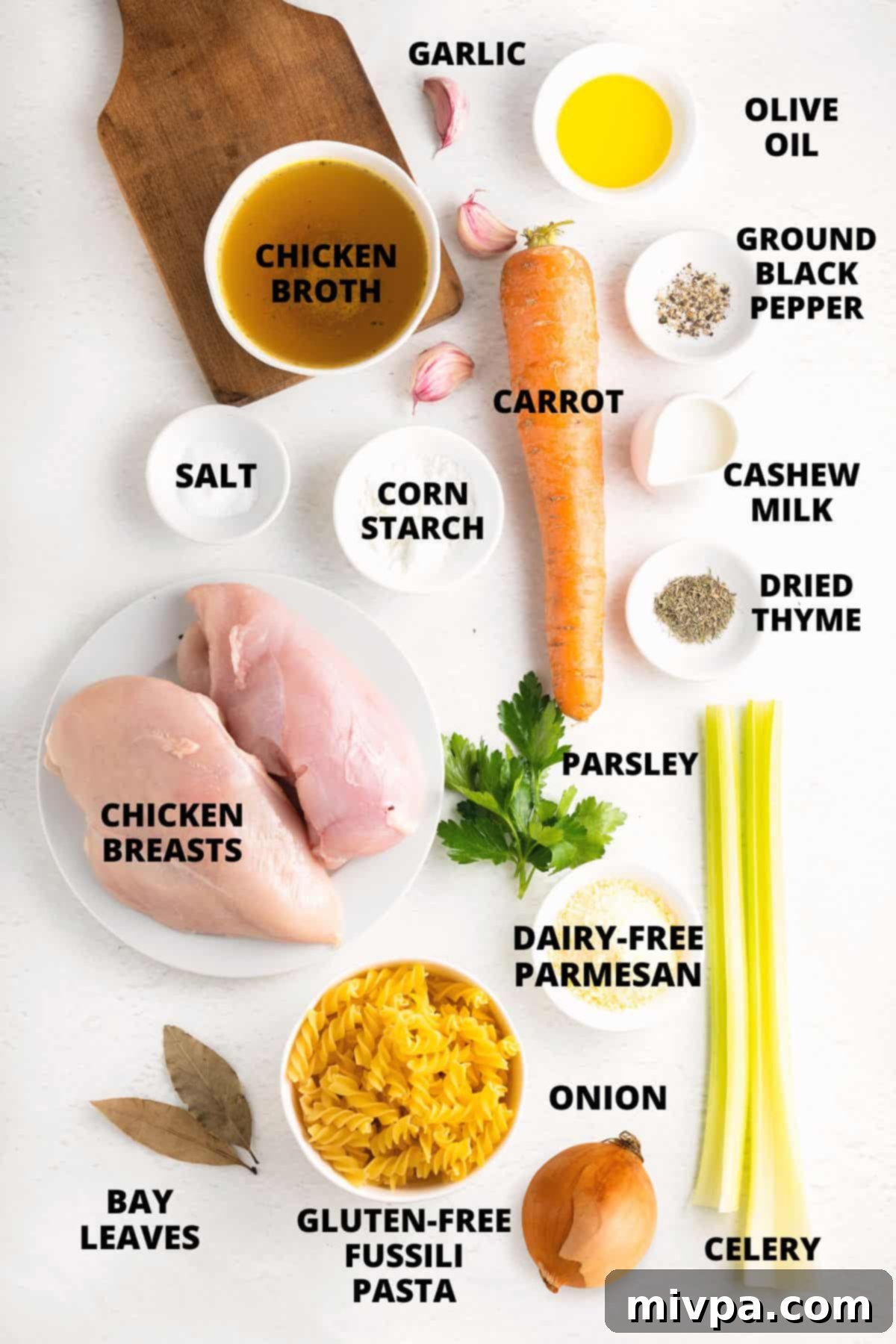 Ingredients for Gluten-Free Chicken Noodle Soup (Dairy-Free) A selection of fresh ingredients laid out on a marble board, including vegetables, chicken, herbs, and gluten-free pasta, ready for making homemade chicken noodle soup.