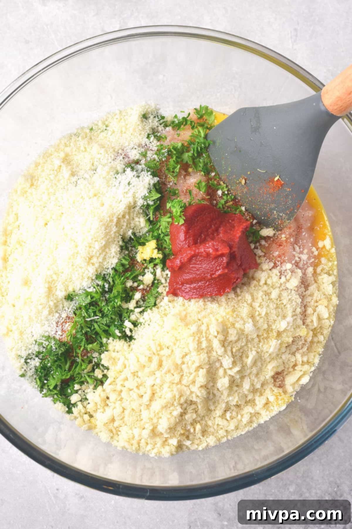 Mixing panko, parmesan cheese and parsley with tomato sauce in a bowl.