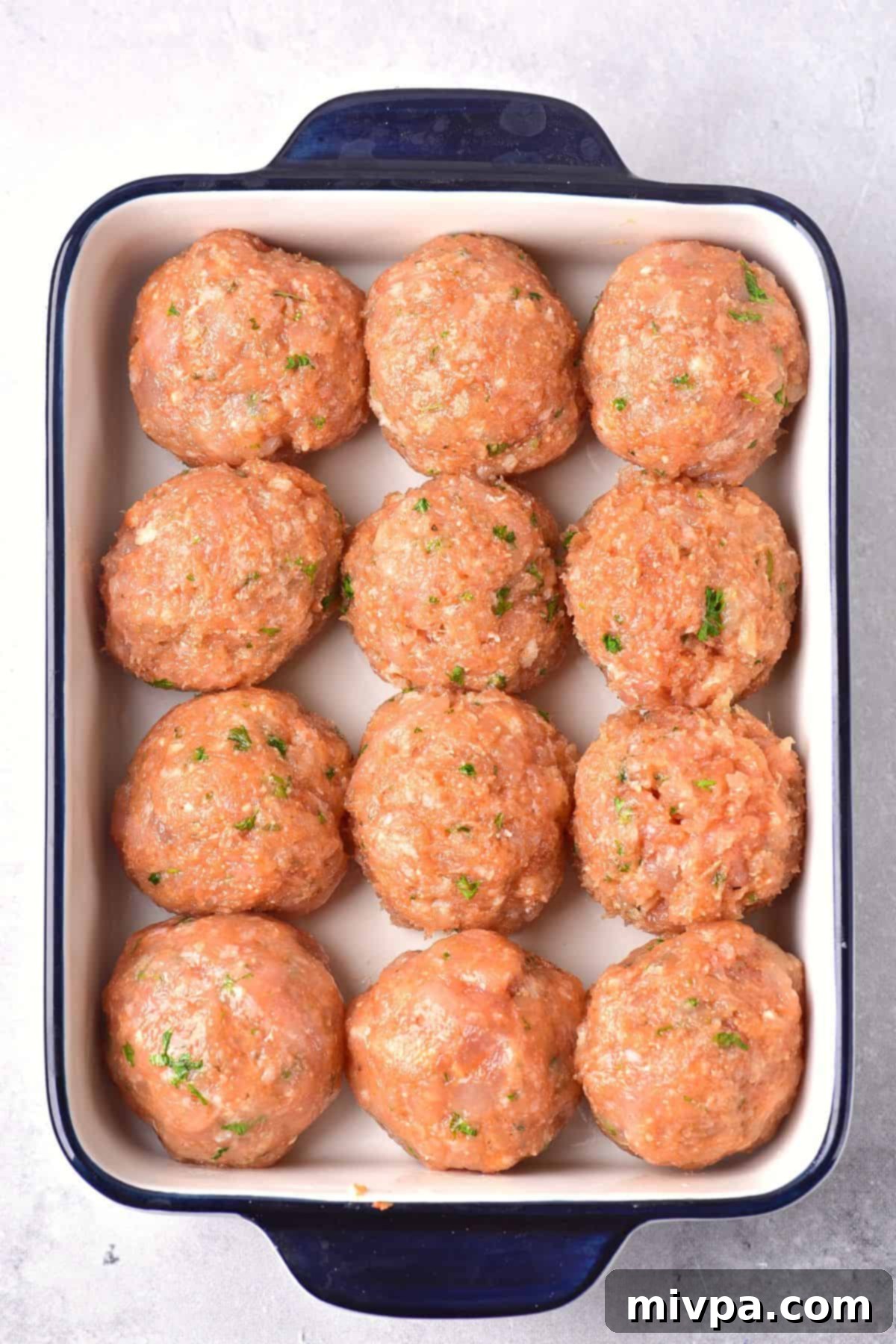 Round balls of ground chicken in a baking dish.