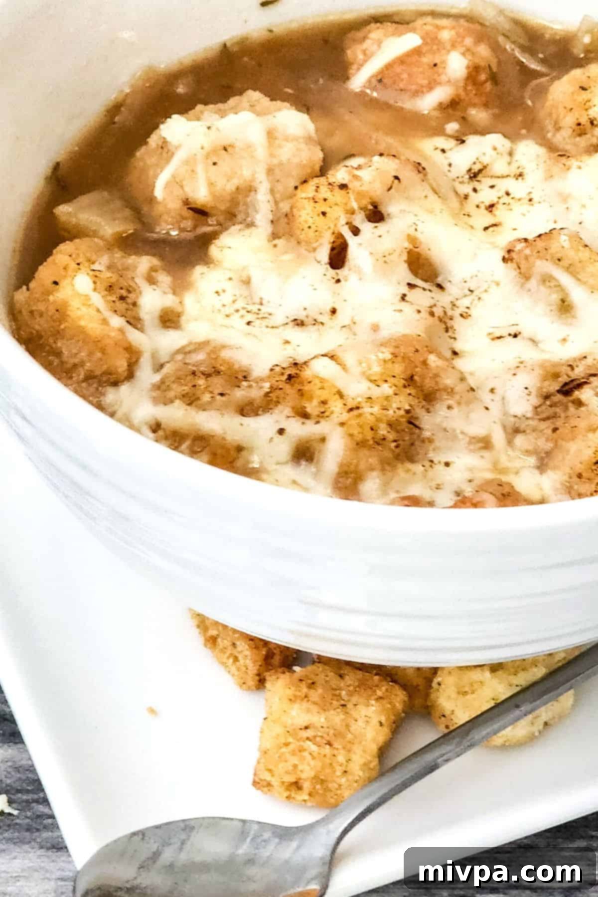 A bowl of gluten-free onion soup on a white plate.