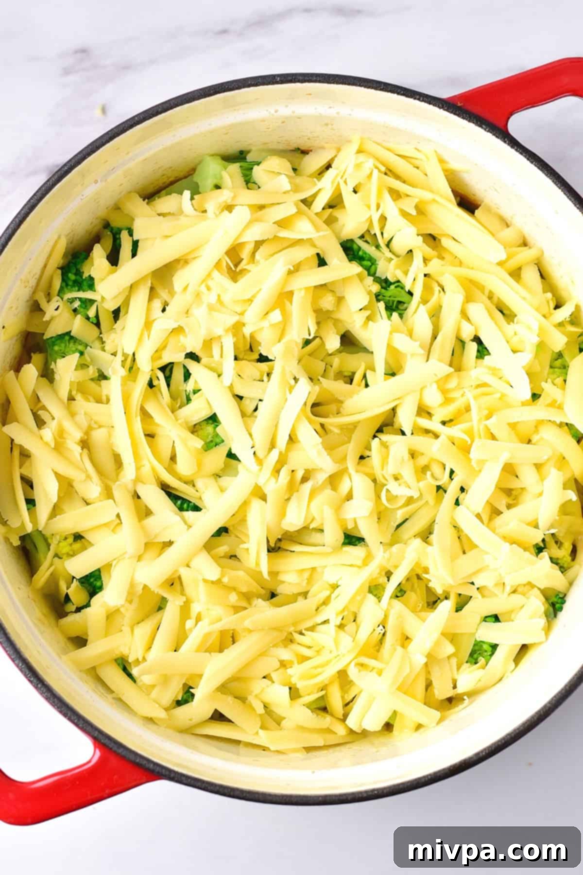 Gluten and Dairy Free Chicken Casserole A Dutch oven filled with chicken and rice casserole, topped with fresh broccoli and shredded dairy-free cheese, ready for broiling.