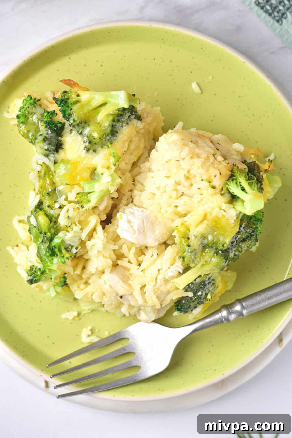 Gluten-Free Chicken Casserole (Dairy-Free) Top down view of a chicken rice casserole on a green plate with a fork, emphasizing its appetizing appearance.