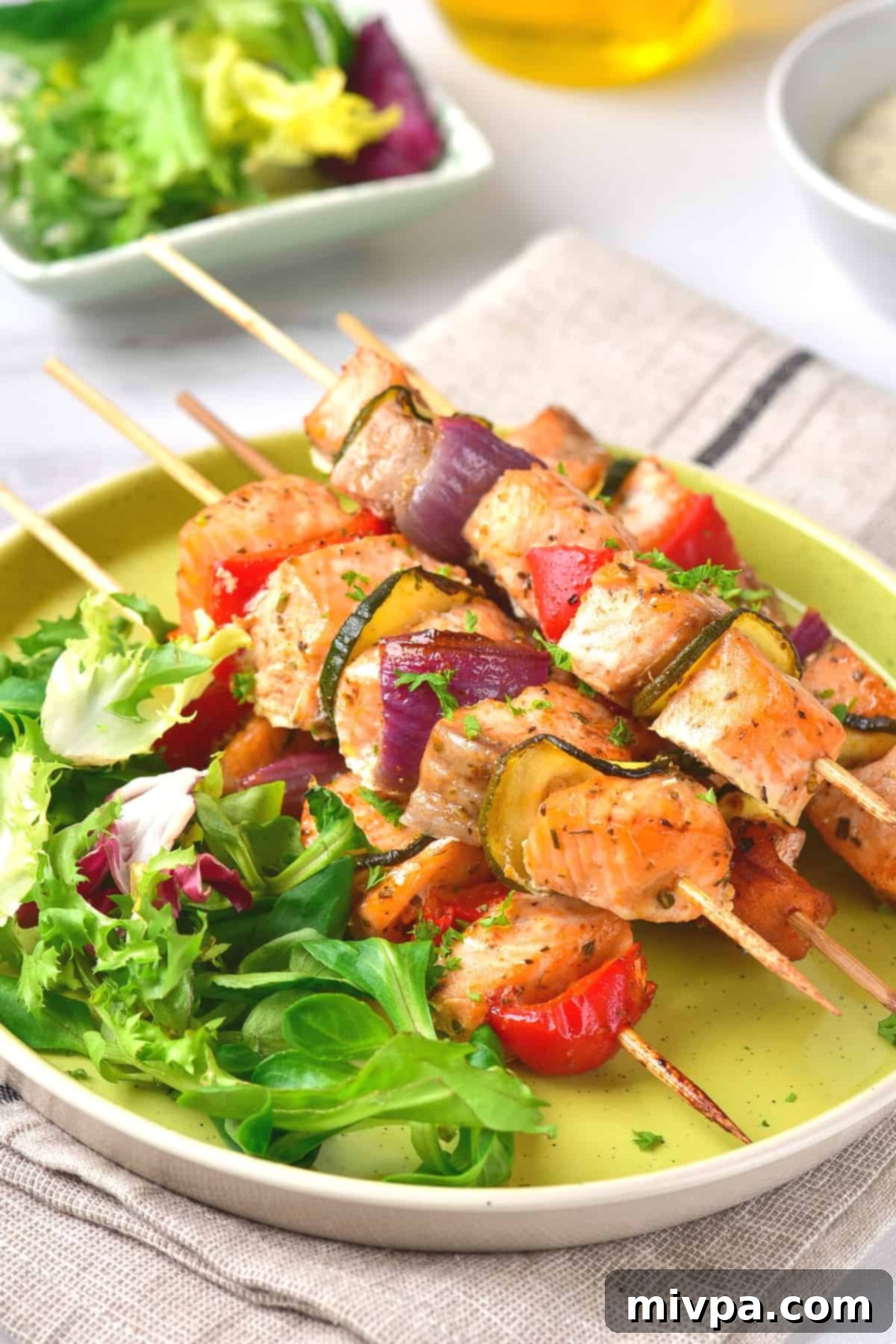 Baked Salmon Kabobs (Gluten-Free, Dairy-Free) Salmon kebabs and salad on round plate.