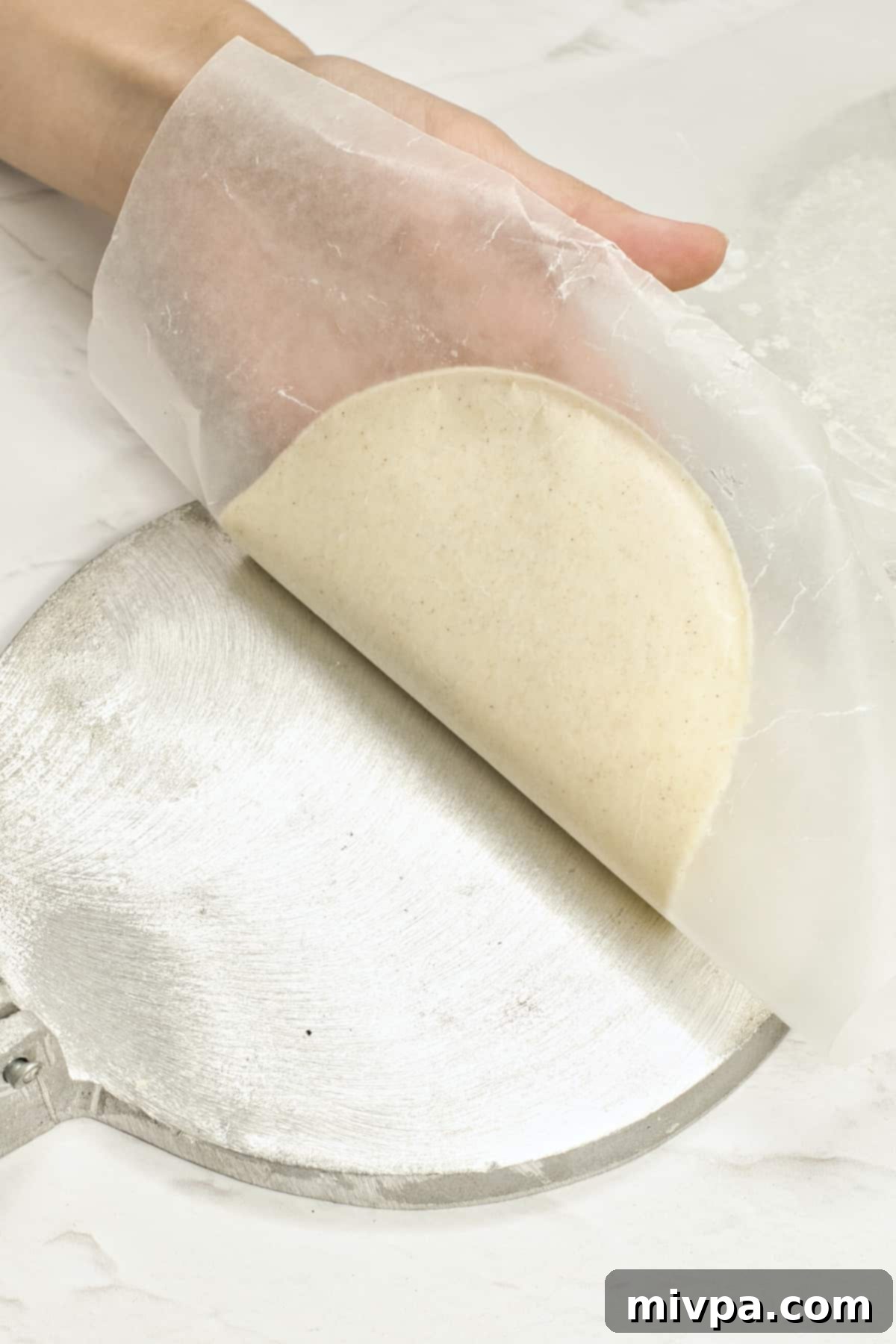 Removing flattened tortilla dough from tortilla press.