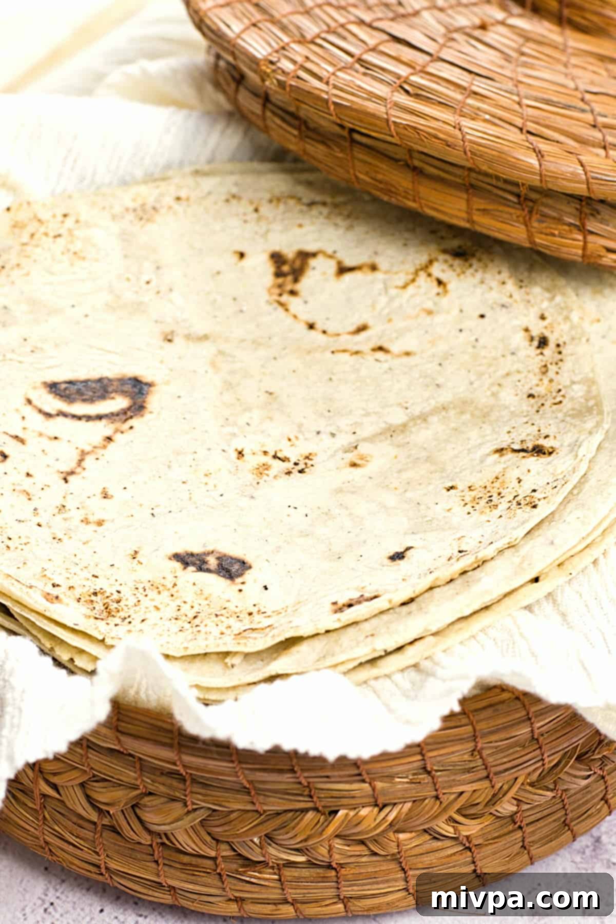 A stack of gluten-free corn tortillas in a bamboo tortilla warmer.