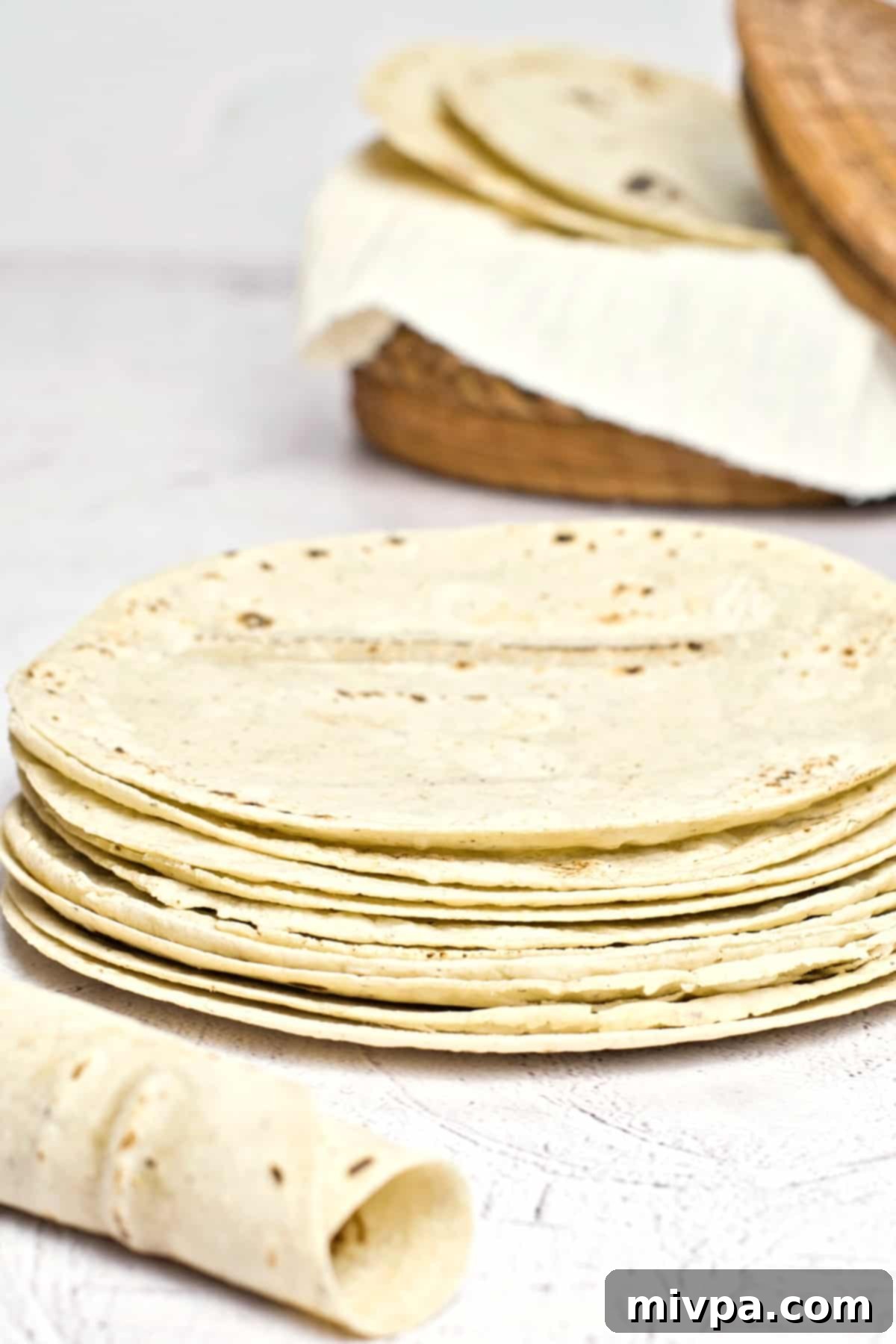 A stack  of homemade tortillas on a board.