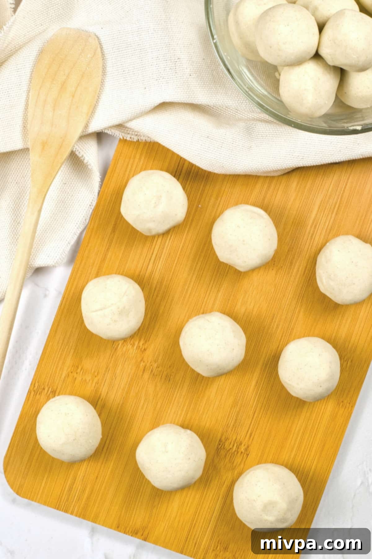 Balls of corn tortilla dough on wooden board.