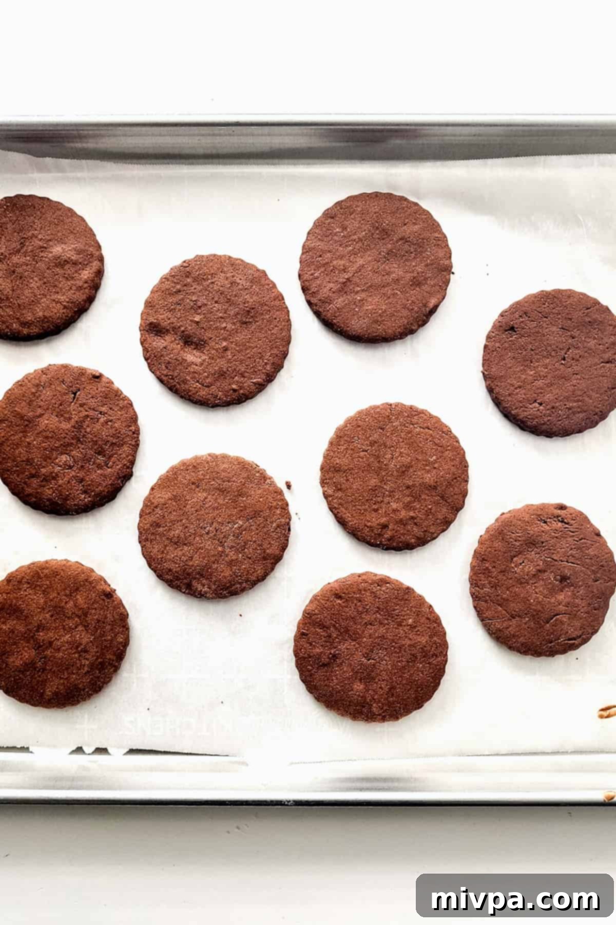 Chocolate cookies on parchment-lined baking sheet.