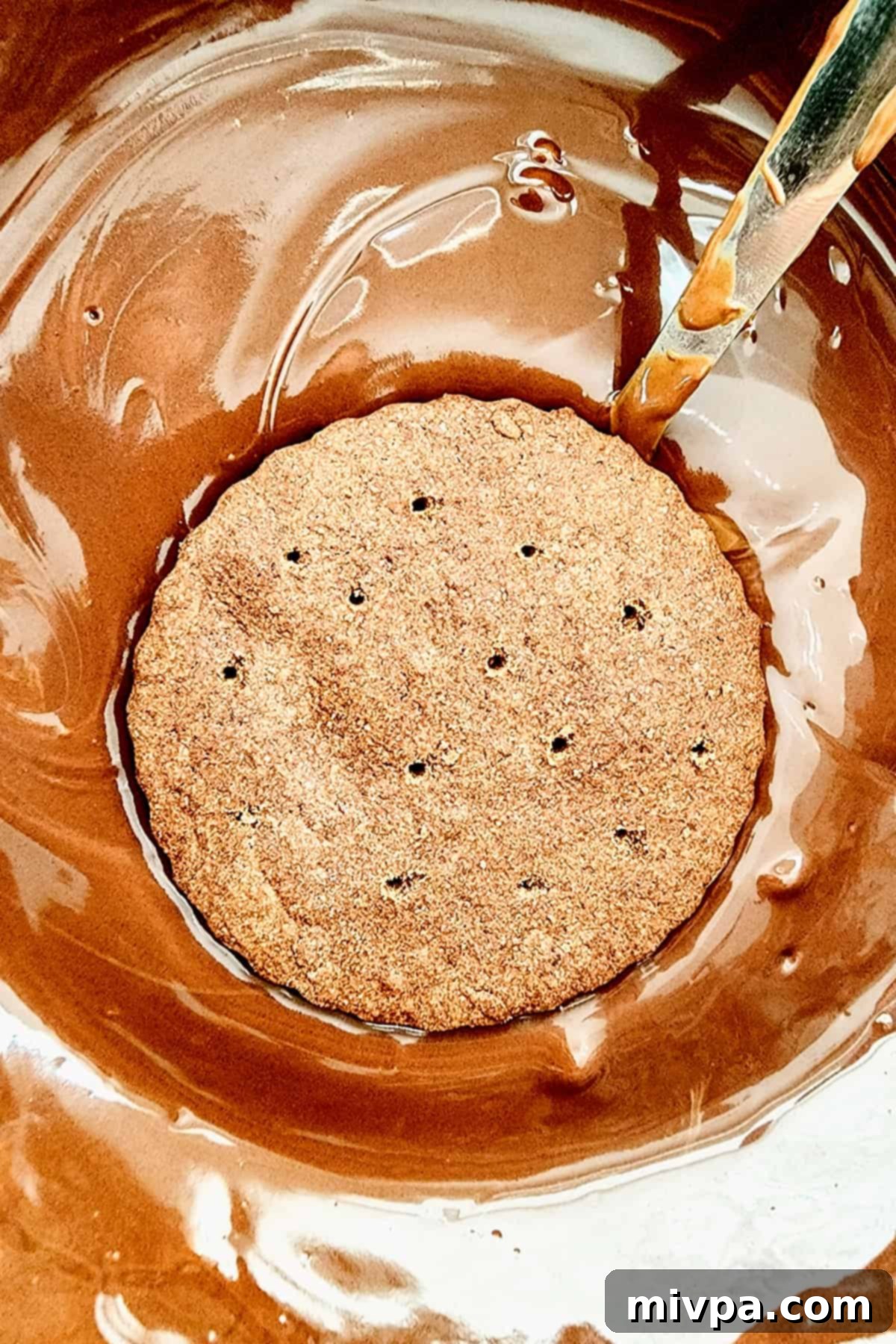 Dipping a chocolate cookie into melted chocolate.