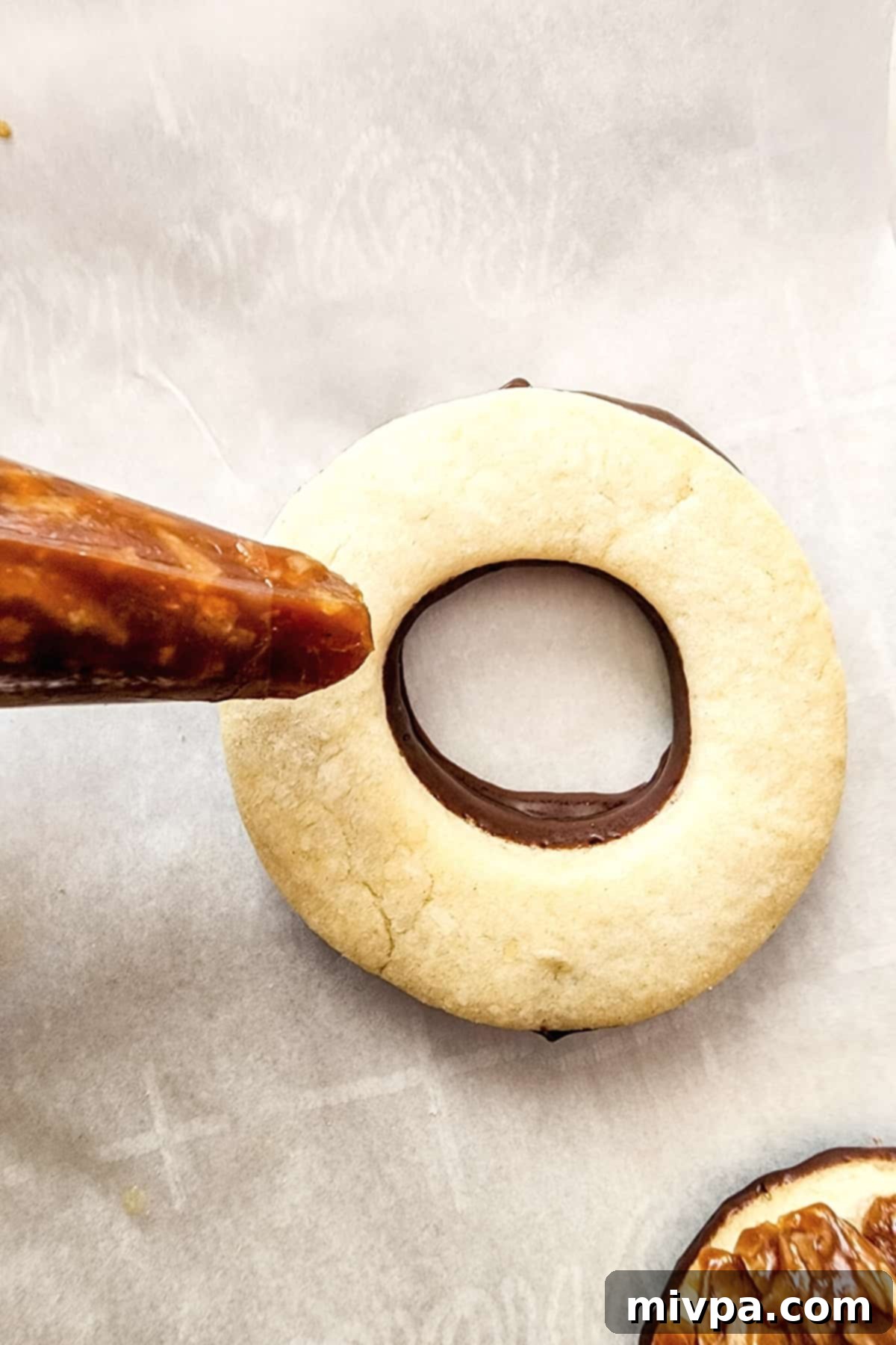 Gluten-Free Copycat Samoas (Dairy-Free) Piping caramel filling on top of cookie.