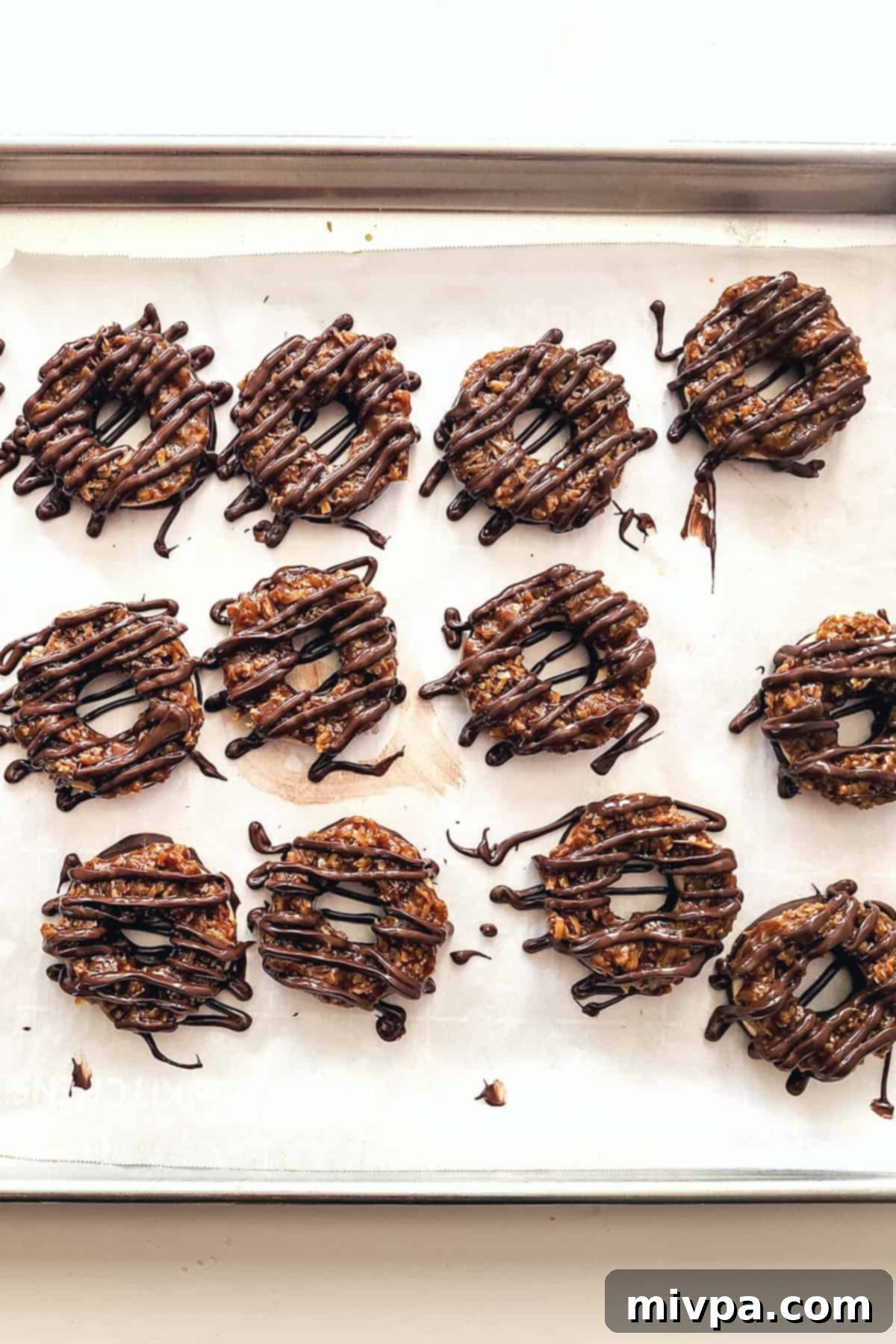 Gluten-Free Samoas Cookies (Dairy-Free) Chocolate drizzled cookies on parchment-lined tray.