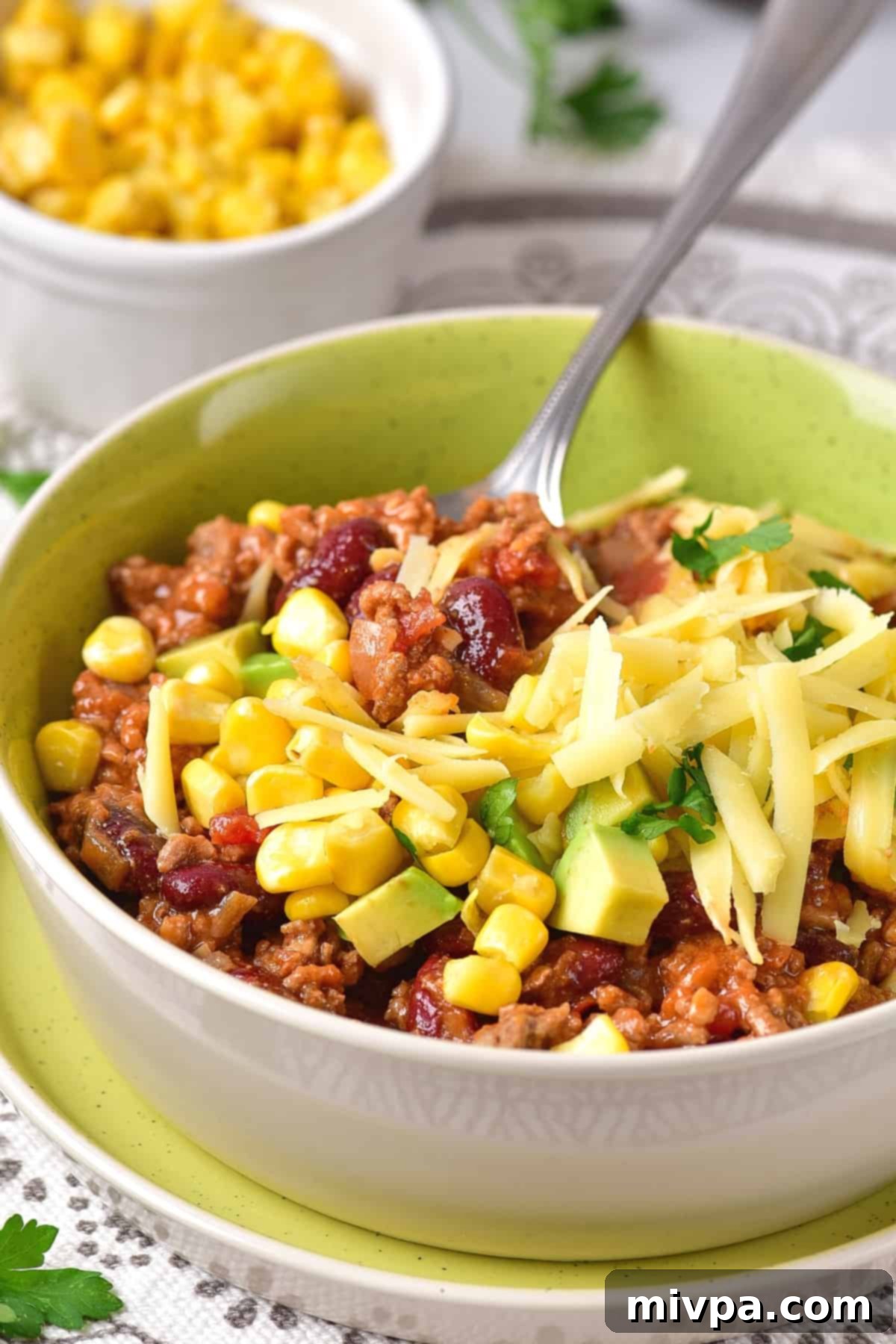 Spoon in a bowl of chili and cheese.