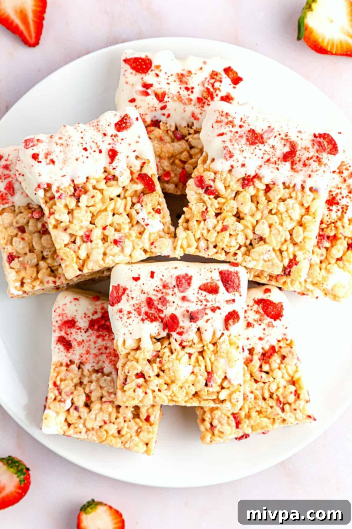 A plate full of strawberry rice krispie treats, many dipped in white chocolate.
