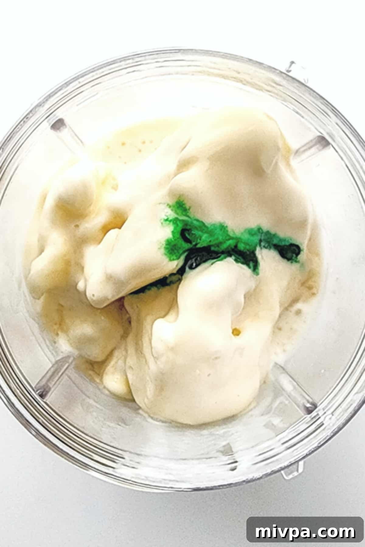 Dairy-Free Shamrock Shake (Gluten-Free) Dairy-free vanilla ice cream, coconut milk, and green food coloring are being added to a high-speed blender.