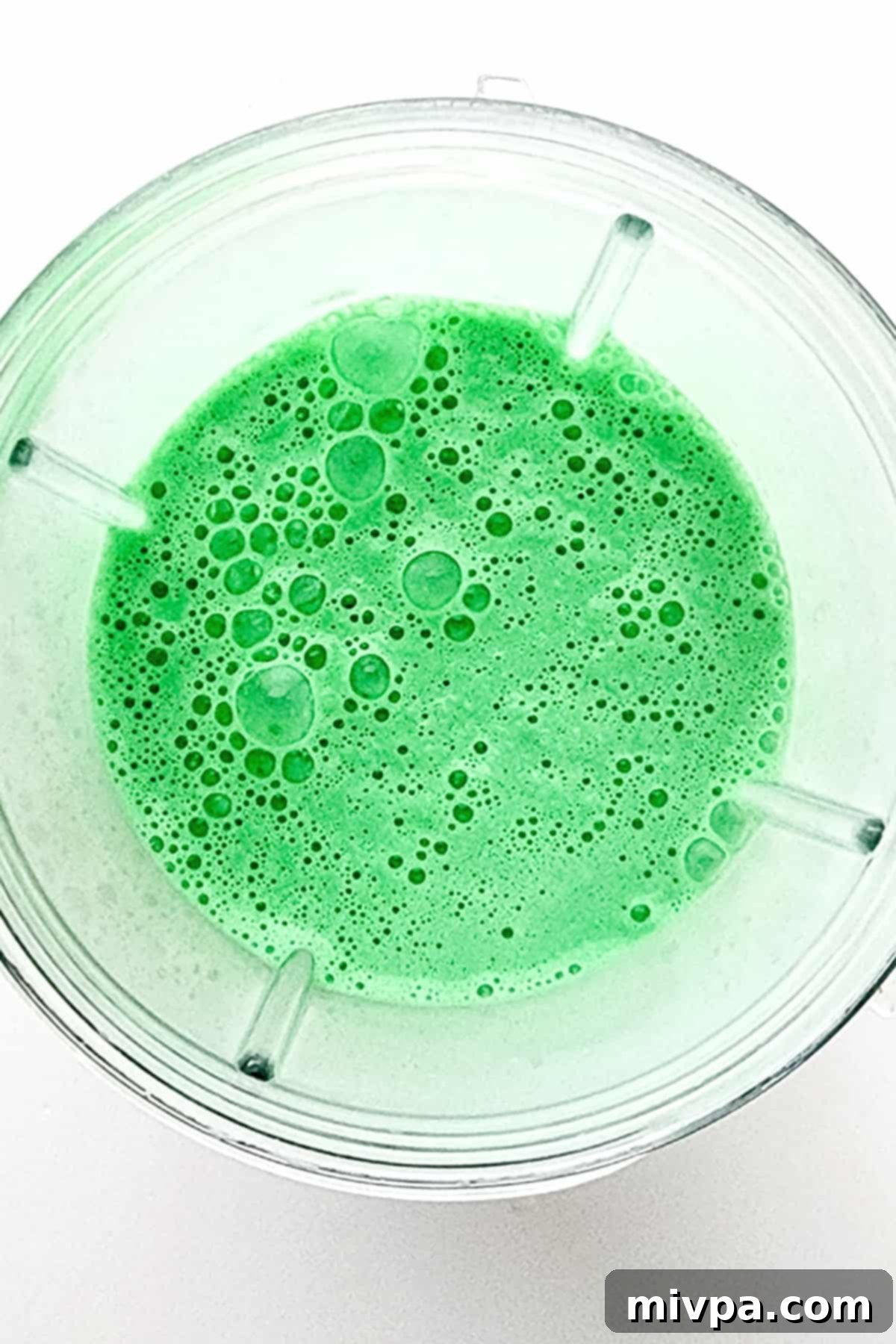 Homemade Vegan Shamrock Shake (Gluten-Free) A high-speed blender containing a vibrant green, creamy mixture, which is the blended vegan shamrock shake.