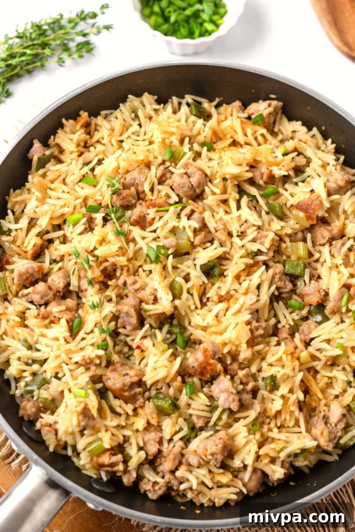 A skillet with sausage dirty rice, ready to be served, showcasing its rich, 'dirty' brown color and delicious texture.