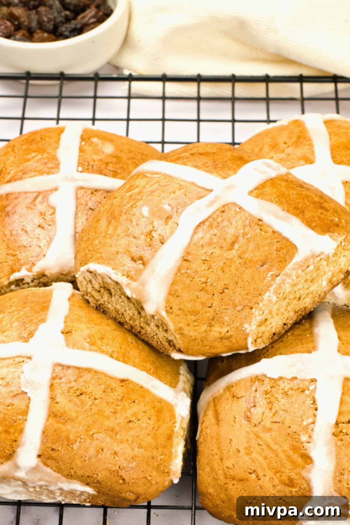 Hot cross buns piled on top of a wire rack, ready for serving.