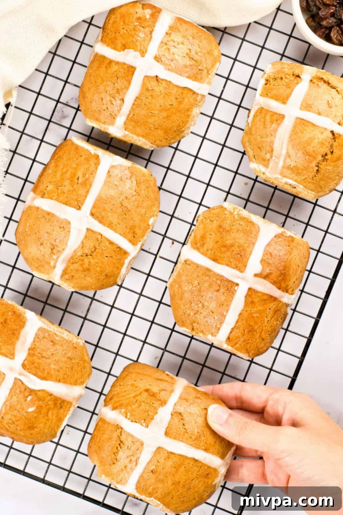Freshly baked gluten-free hot cross buns cooling on a wire rack.
