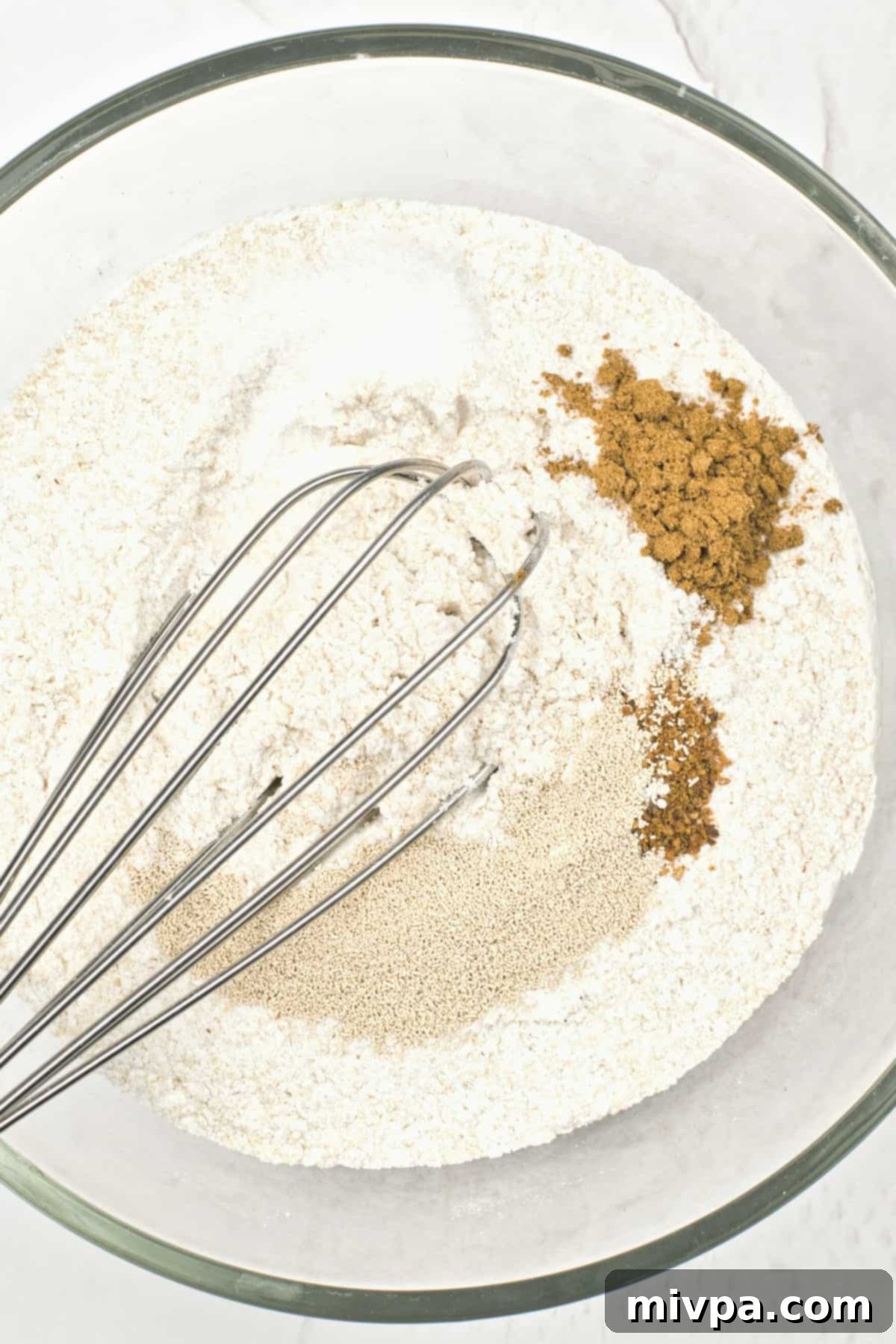 Whisking gluten-free flour and dry spices in a glass mixing bowl.