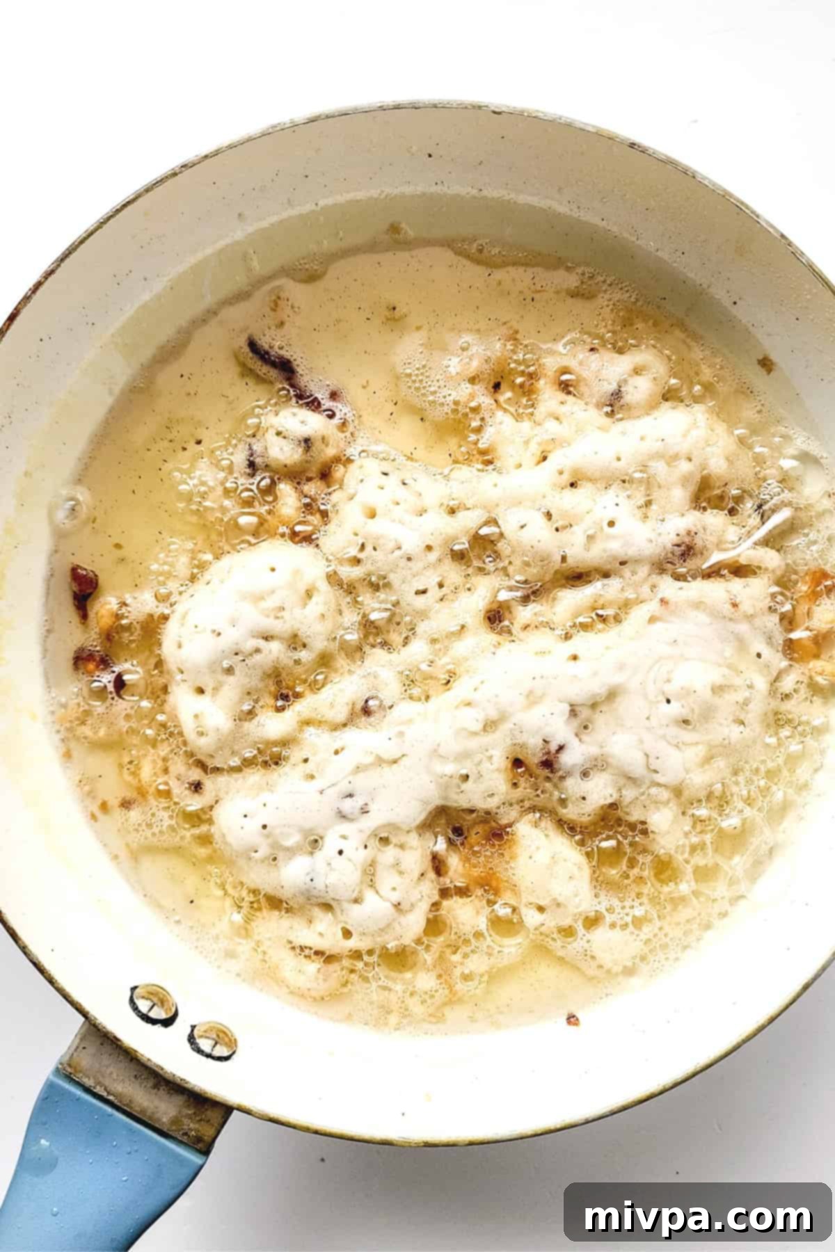 Gluten-free funnel cake batter being piped into hot oil, cooking rapidly.