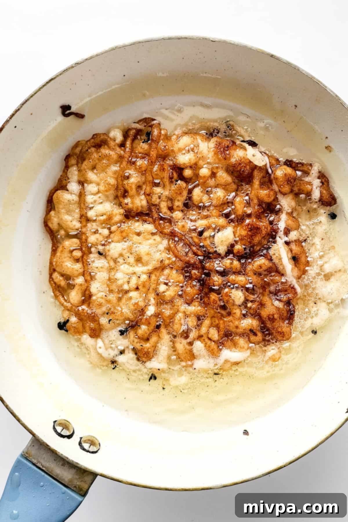 Gluten-free funnel cake cooking in hot oil, achieving a perfect golden color.