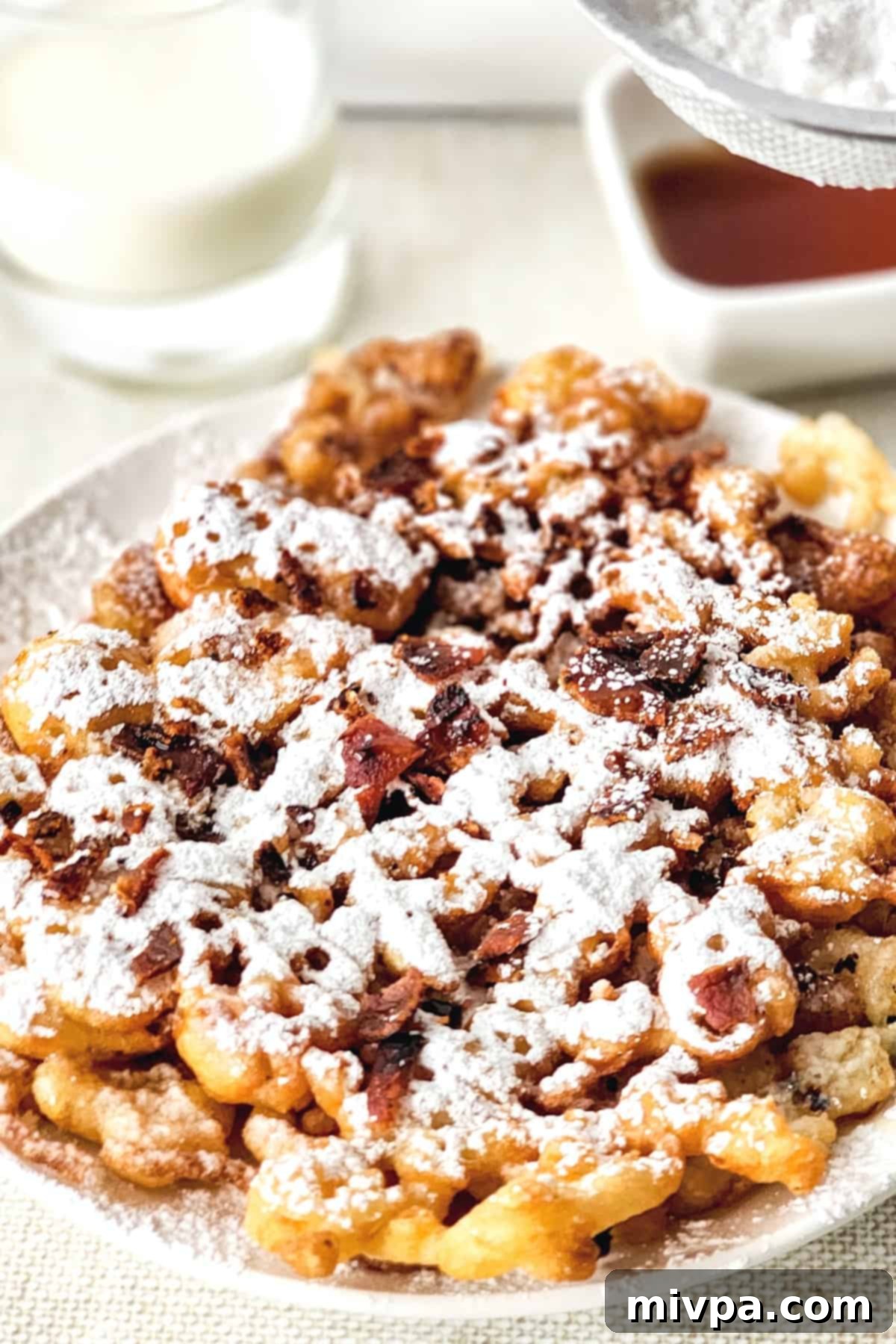 A plate of warm gluten-free funnel cakes beautifully dusted with powdered sugar.