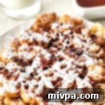A plate of freshly fried gluten-free funnel cakes with powdered sugar.