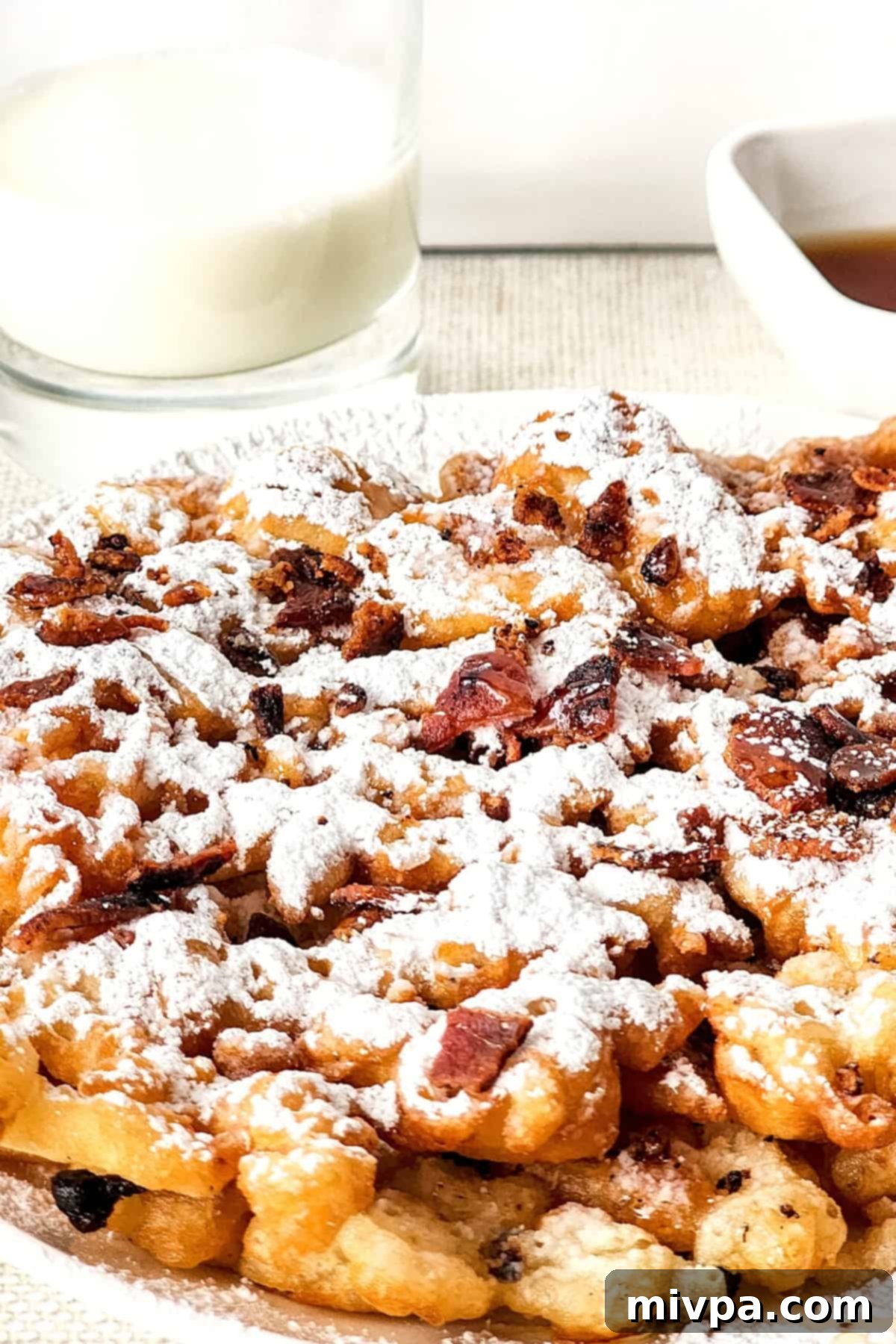 Close-up view of a gluten-free funnel cake beautifully sprinkled with powdered sugar.