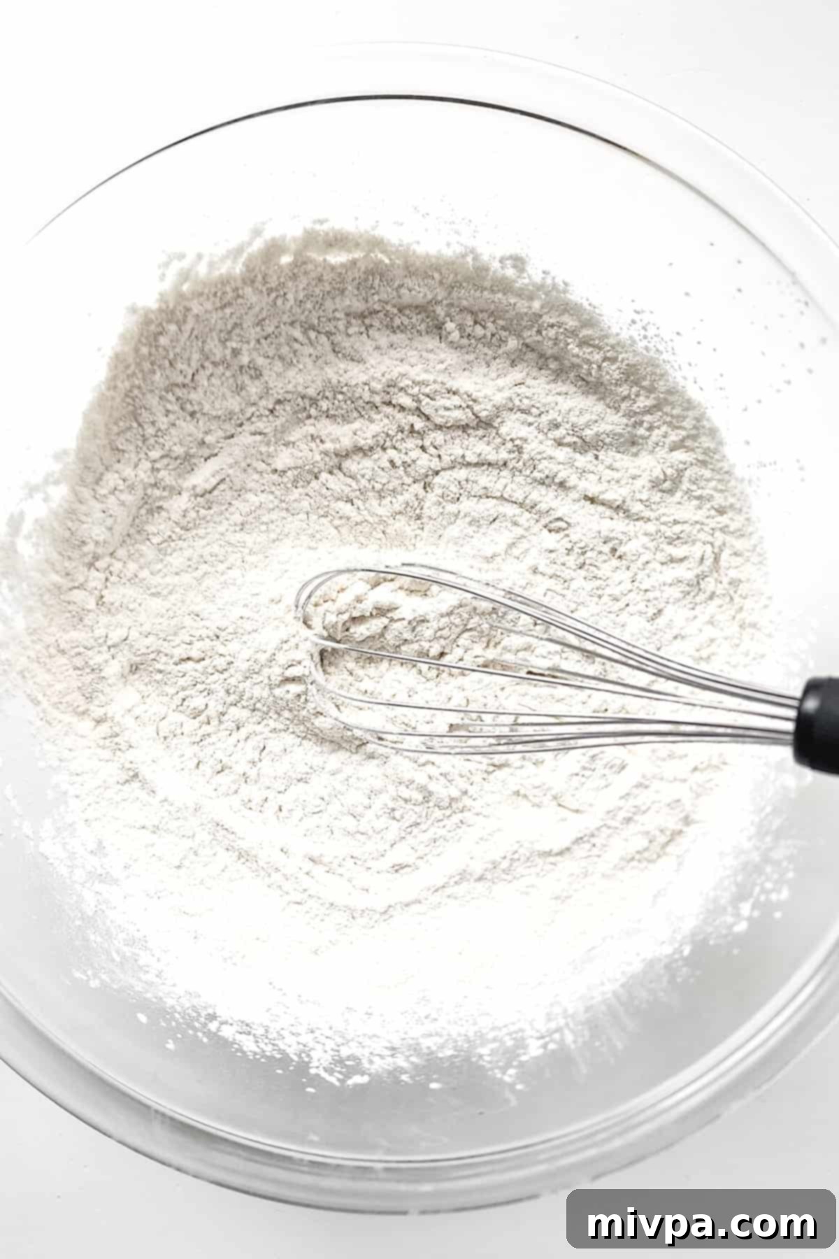 Whisking together the gluten-free flour mixture in a glass mixing bowl.