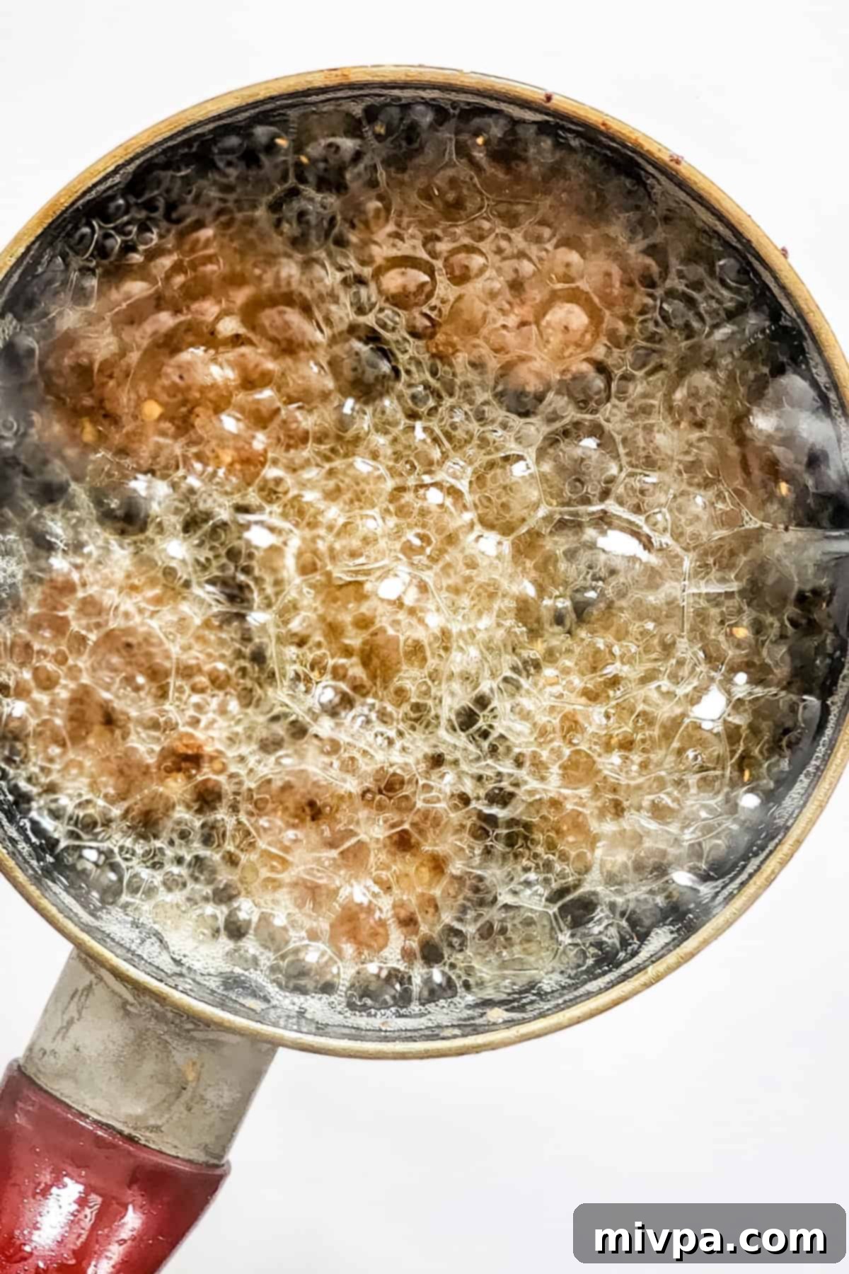 Crispy dill pickle chips being deep-fried in a pot of hot vegetable oil, turning golden brown.