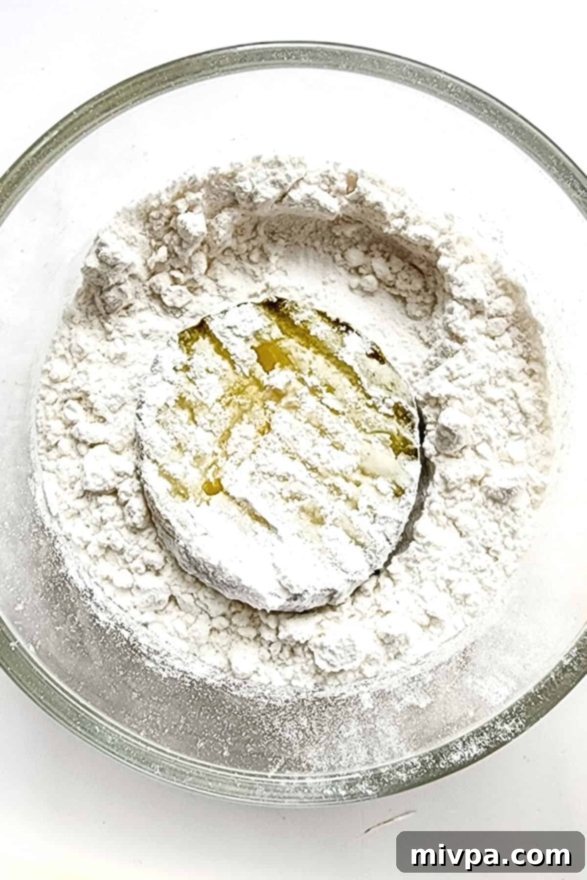 A hand coating a pickle slice evenly in a bowl of gluten-free flour.