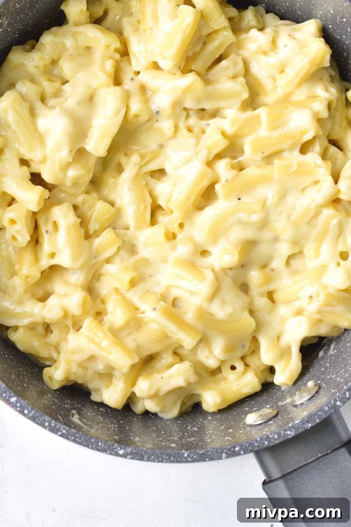 Macaroni pasta coated with cheesy sauce in a pan.