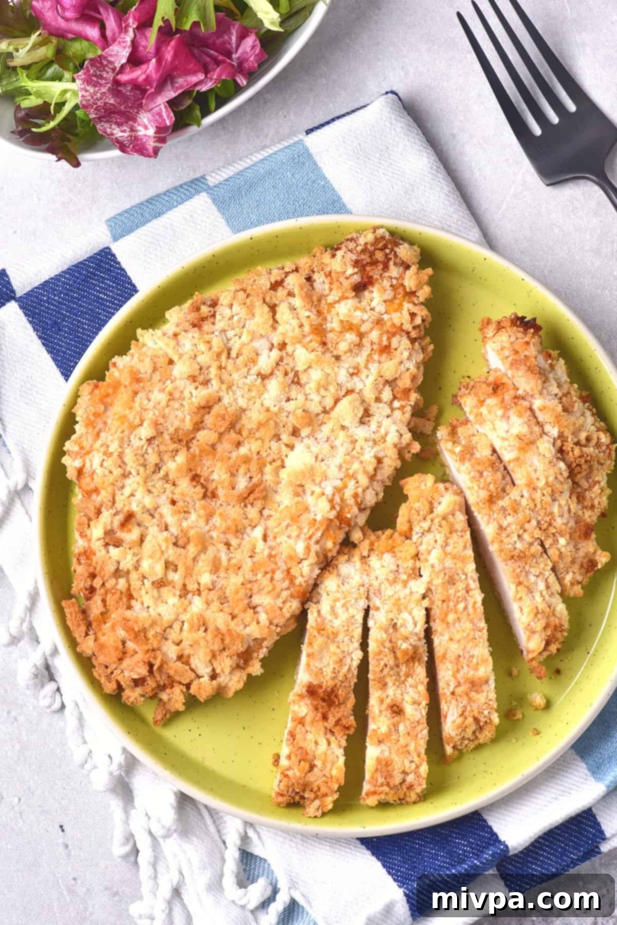 Air fryer chicken cutlets on green plate on blue and white napkin.