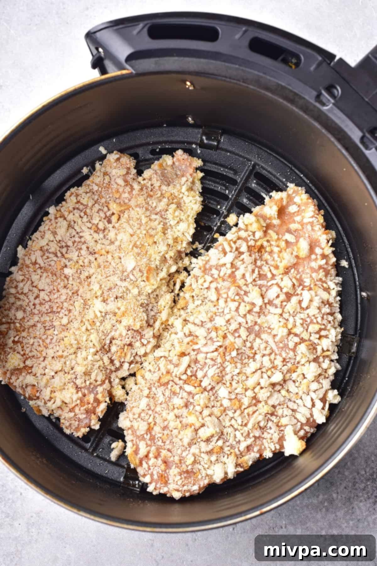 Breaded chicken cutlets to be cooked in air fryer basket.