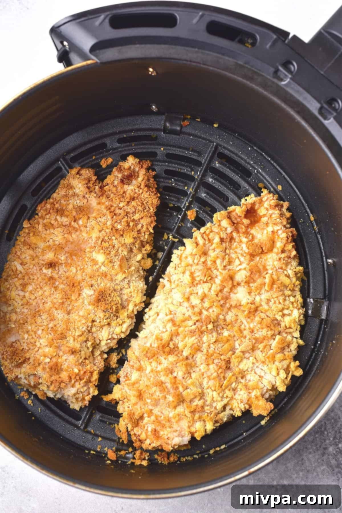 Crispy golden brown chicken cutlets in air fryer basket.