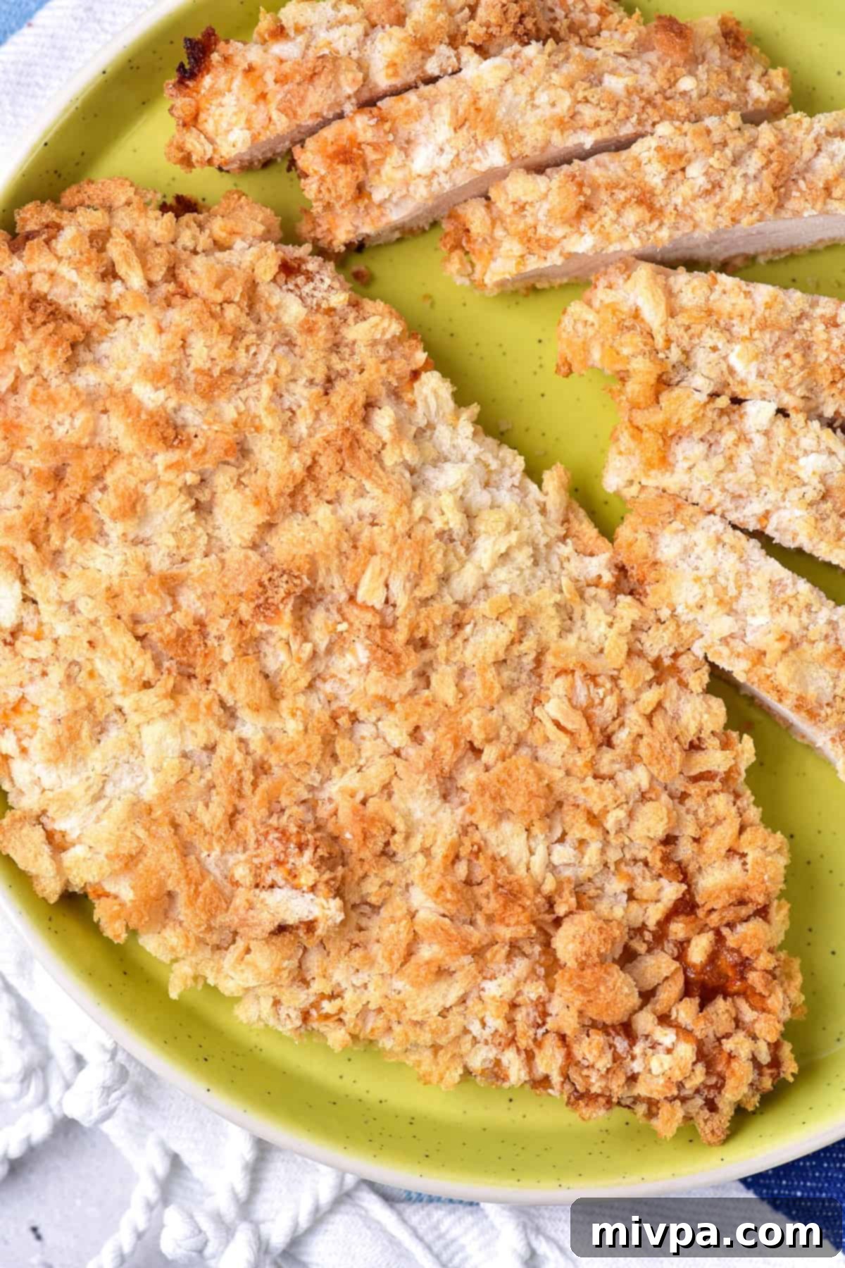 Sliced pieces of breaded chicken breast on green plate.