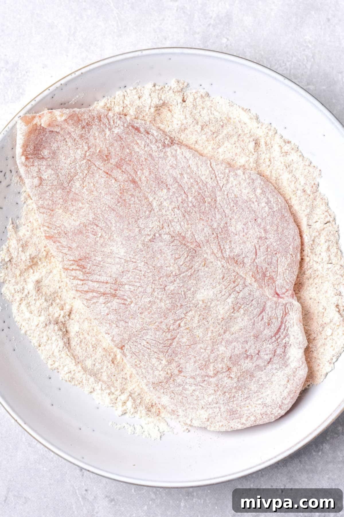 Coating chicken cutlet with flour.