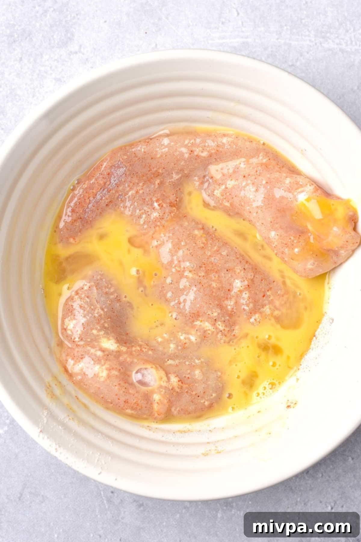 Dipping chicken cutlets in beaten egg mixture.