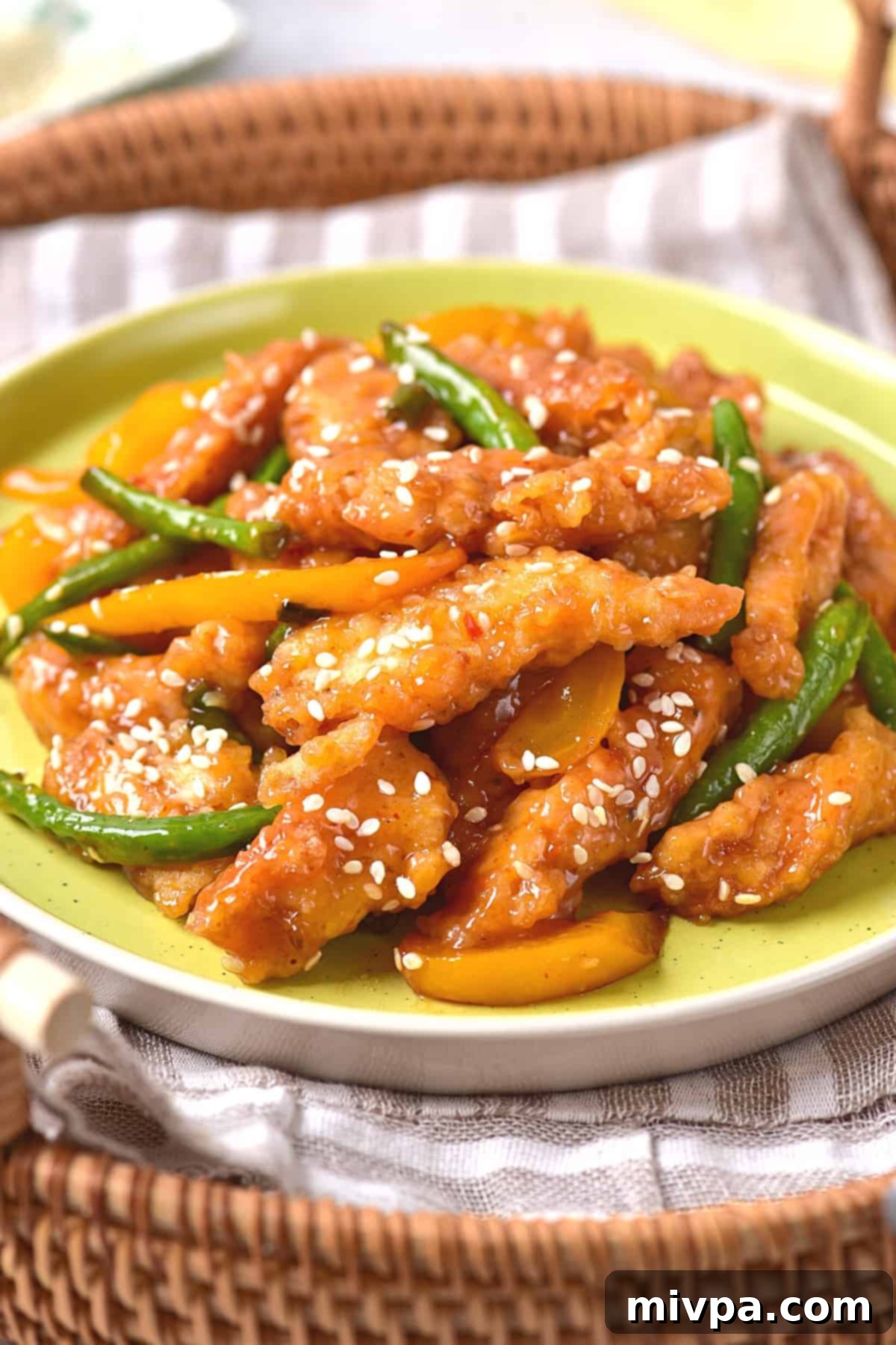 An appetizing close-up of a finished plate of homemade honey sesame chicken and vibrant sautéed vegetables, garnished with white sesame seeds. The dish is beautifully presented, showcasing the crispy texture of the chicken and the rich, glossy sauce, ready to be enjoyed. This final shot highlights the delicious result of the gluten-free recipe.