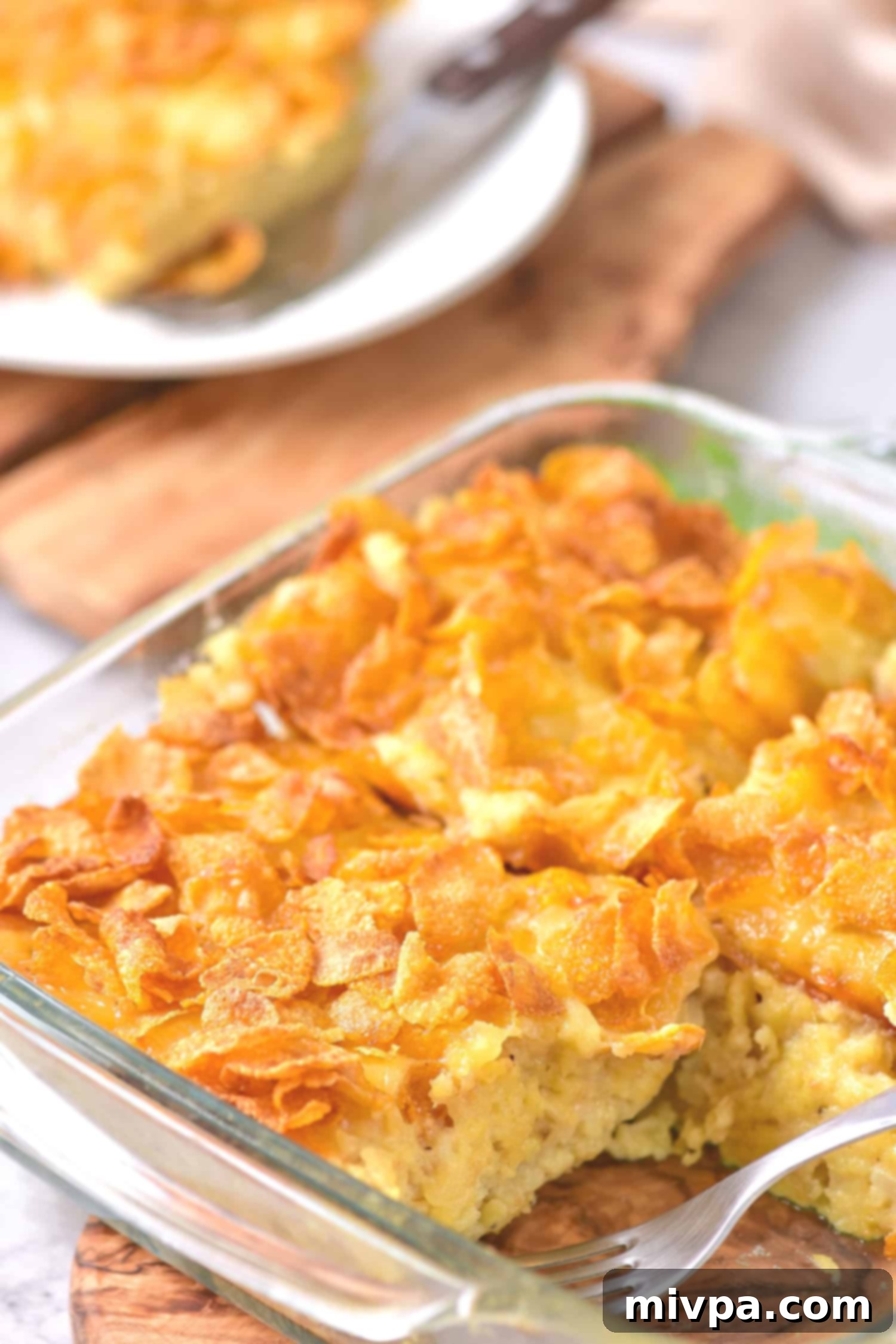 Half-eaten gluten free hashbrown casserole in a white baking dish, showing the layers.