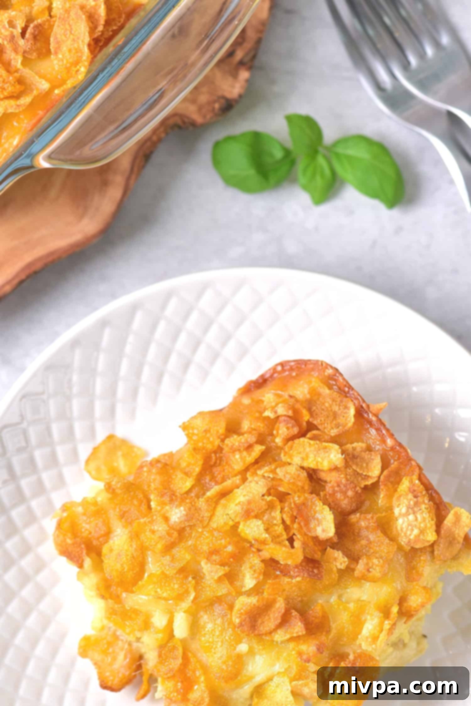 A portion of gluten free hash brown casserole on a white plate, garnished with fresh herbs.