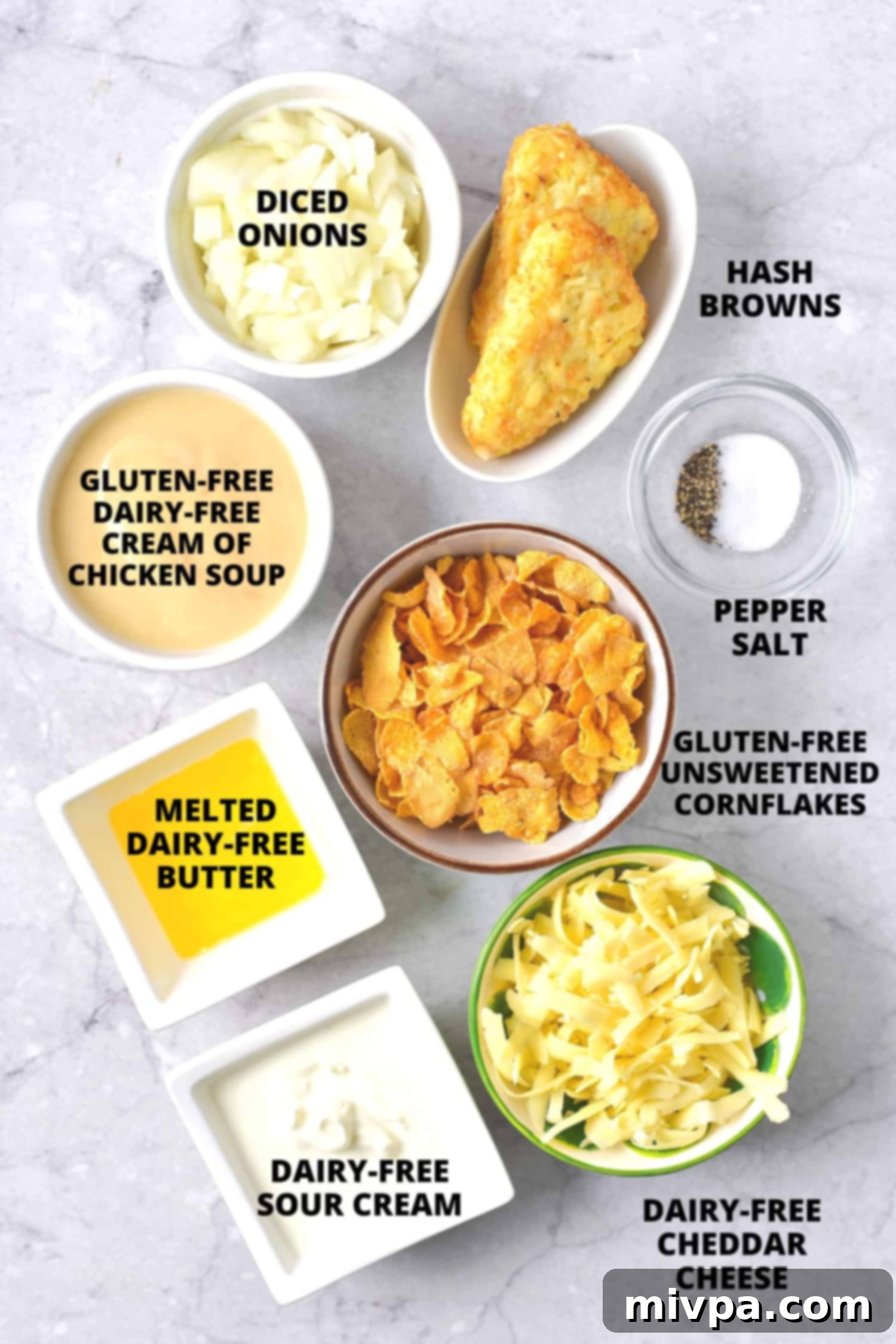 Ingredients for gluten-free hash brown casserole laid out on a marble board, including hash browns, onion, spices, and dairy-free products.