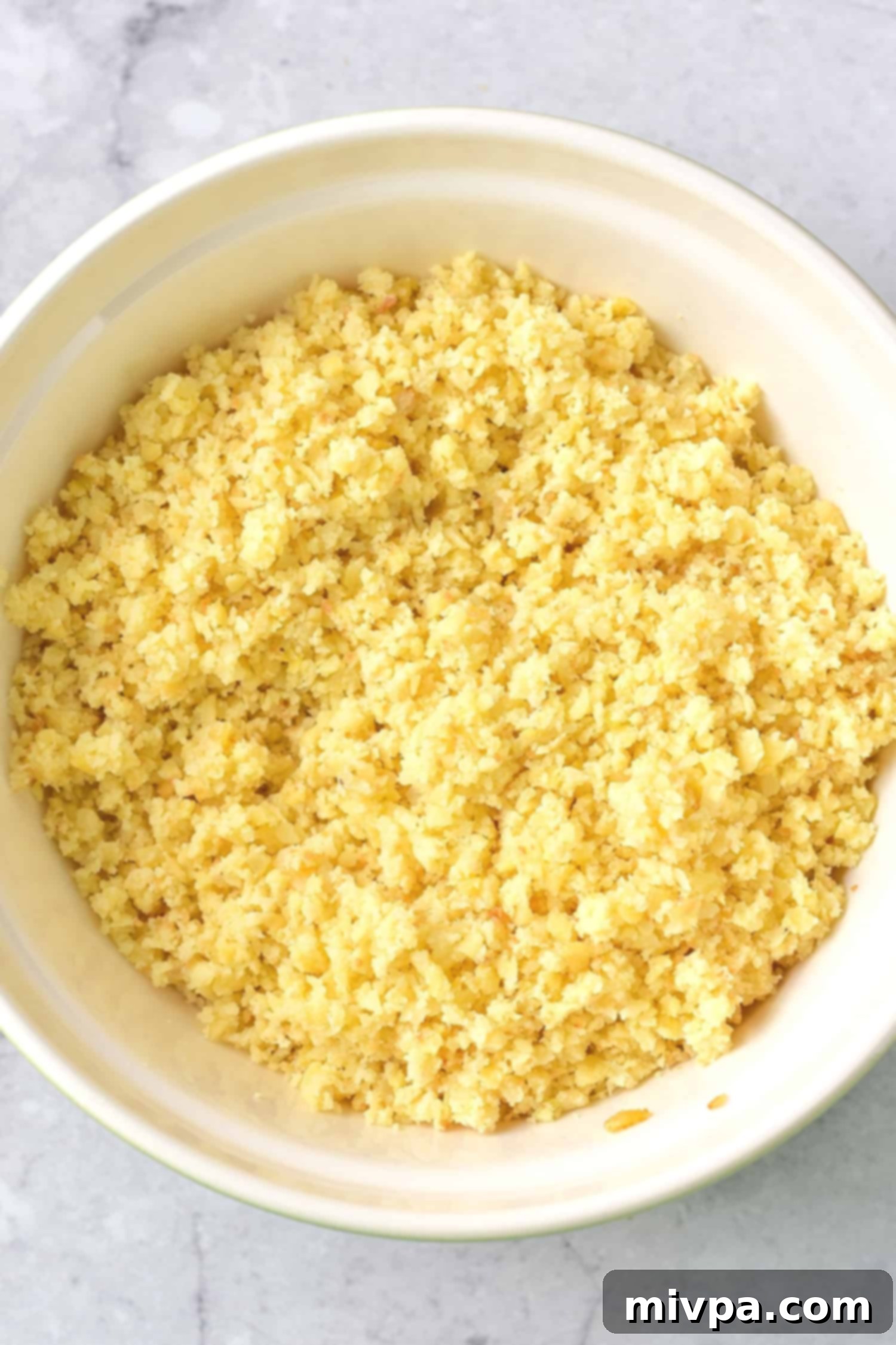 Processed hash browns in a white bowl, showing a fine, rice-like consistency.