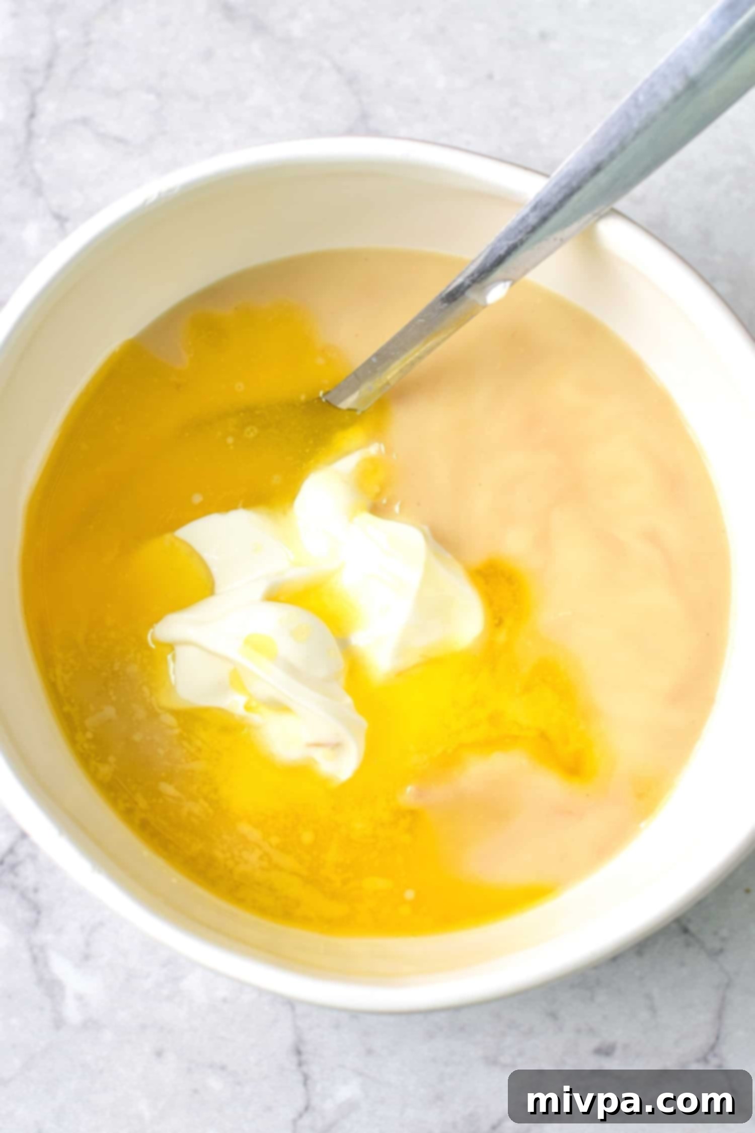 Mixing melted butter, sour cream, and cream of chicken soup in a bowl until smooth.