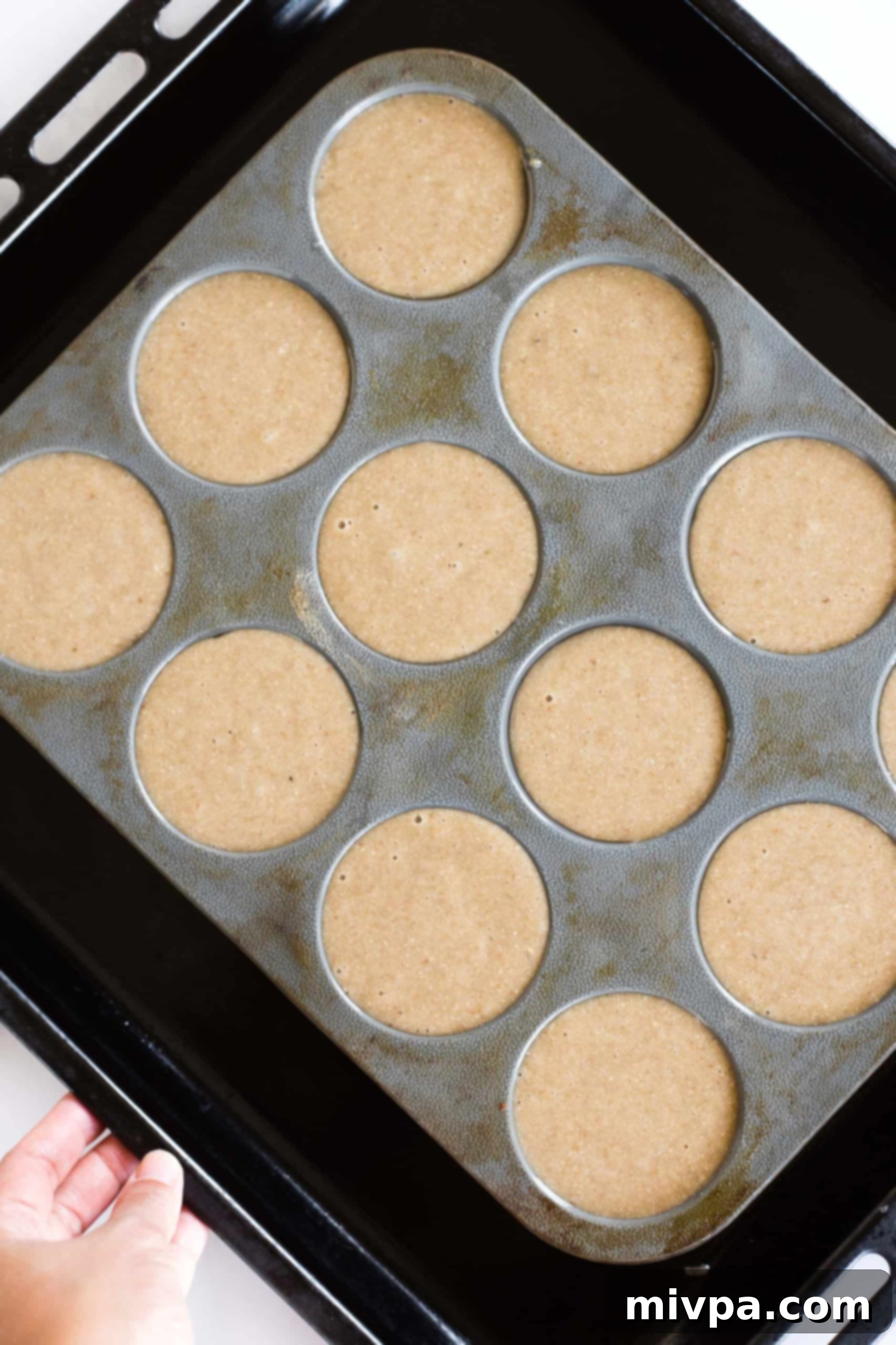 A muffin mold filled with buckwheat muffin batter, ready for the oven.