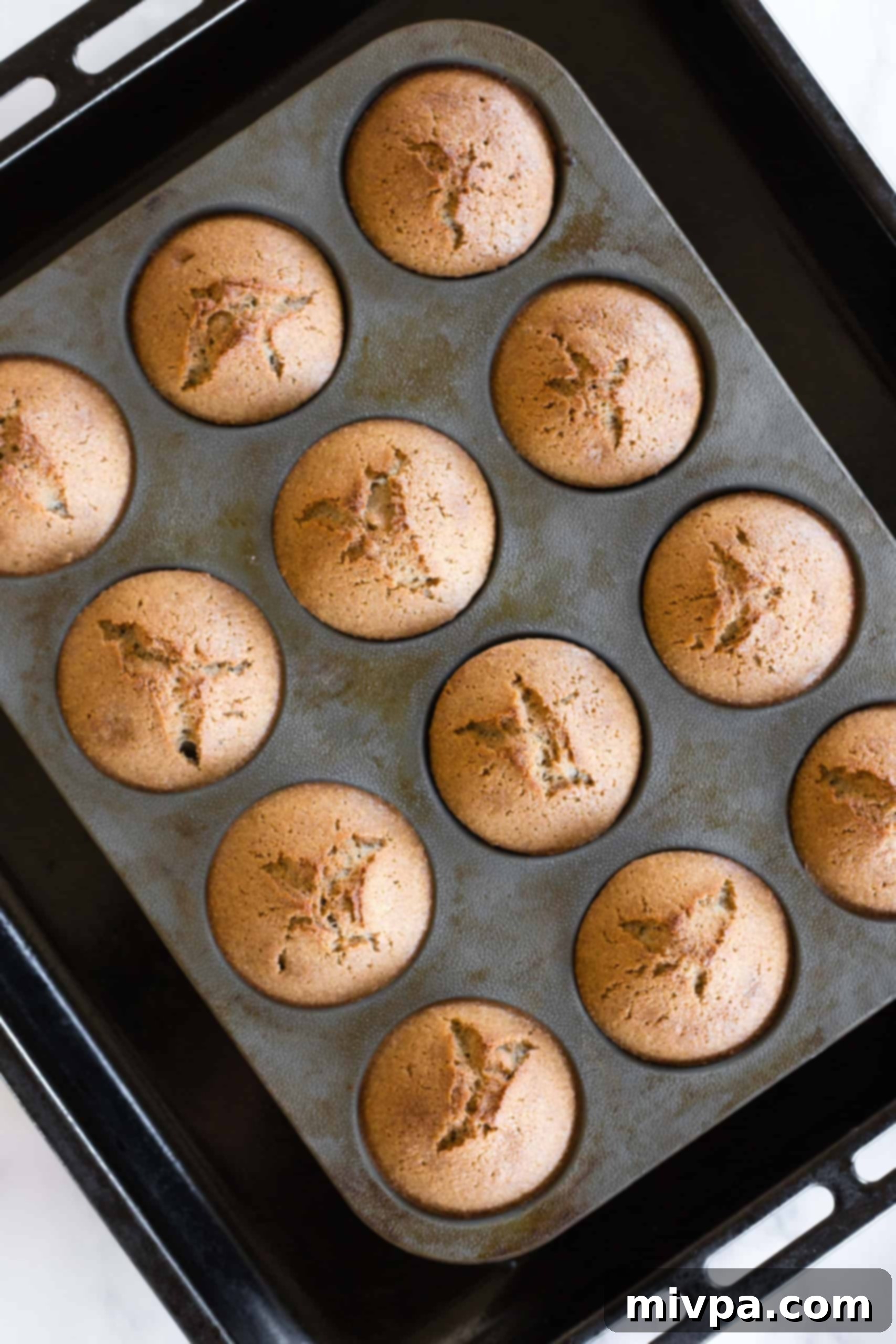 Freshly baked buckwheat muffins, golden brown and perfectly domed, in a silicon muffin mold.
