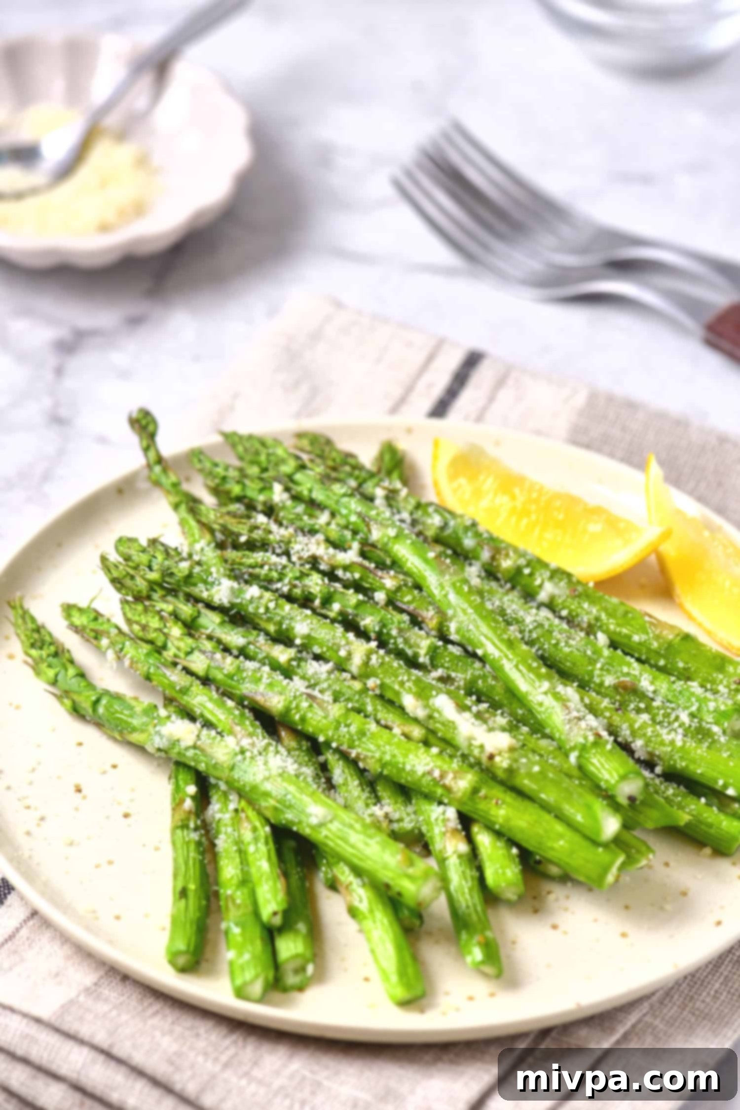 Parmesan asparagus with lemon wedges beautifully plated.