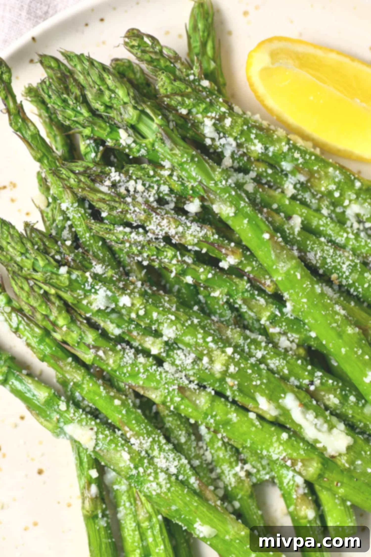 Up close shot of air fried asparagus sprinkled with parmesan cheese, highlighting its crispy texture.