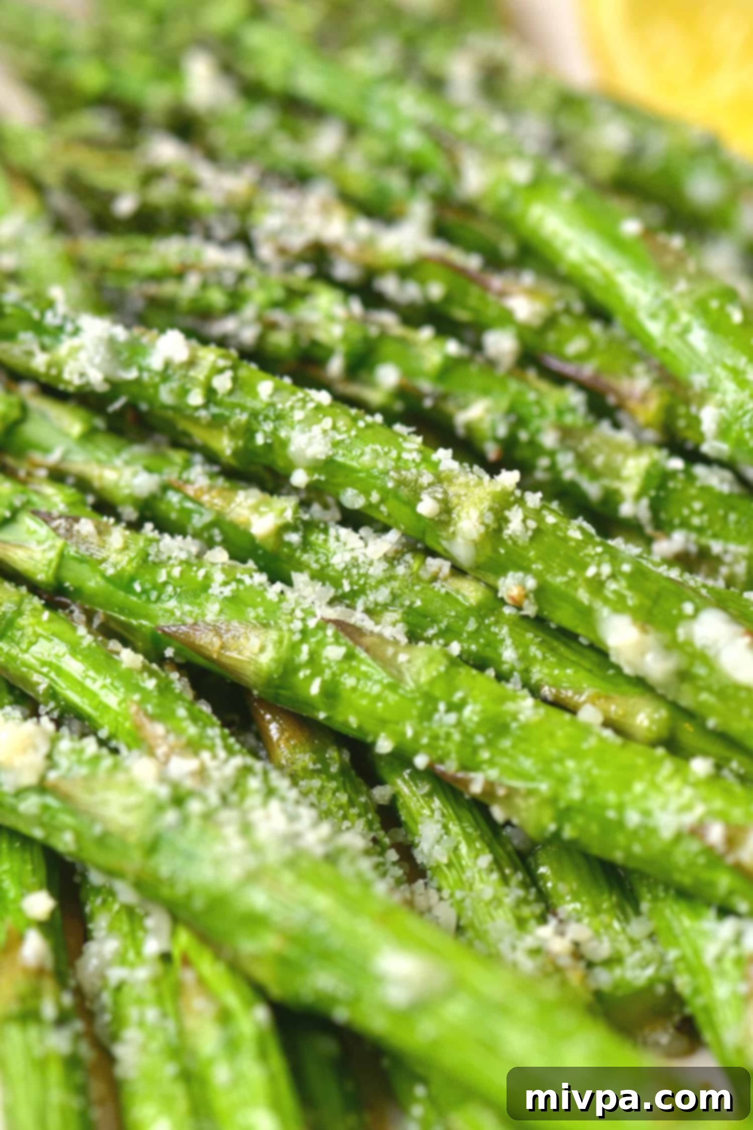 A close-up of air-fried asparagus spears with parmesan and lemon wedges, showcasing the delicious result.