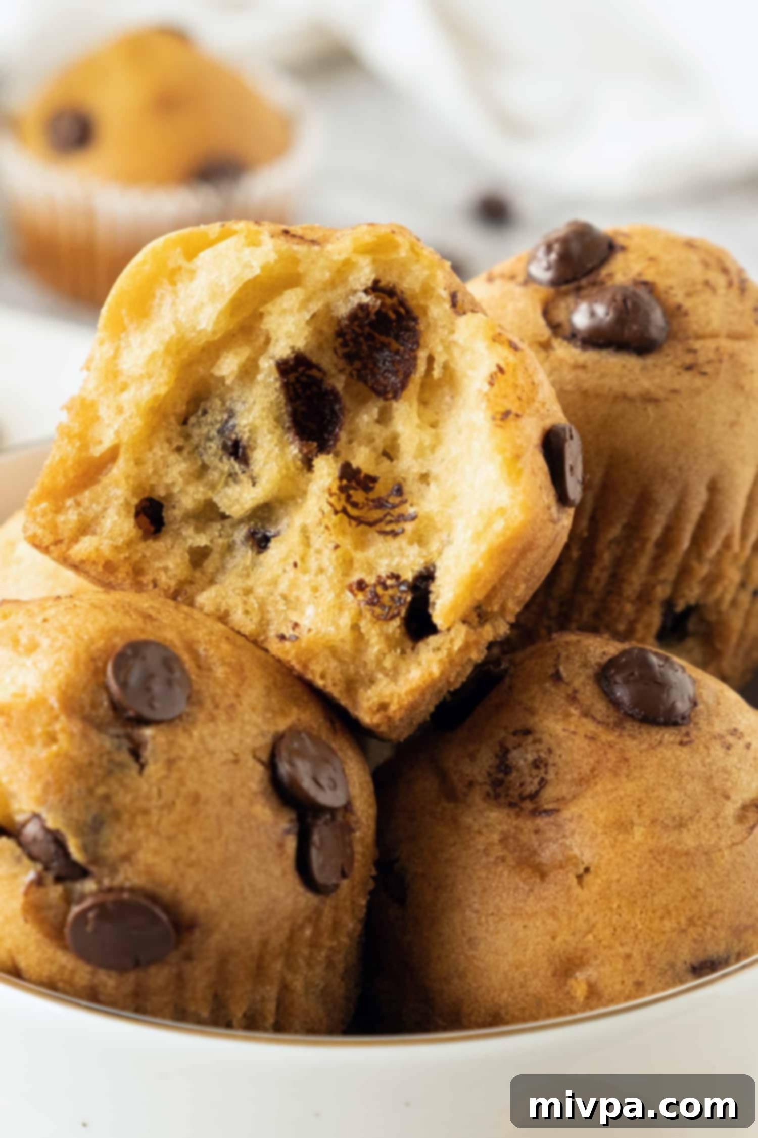 Gluten-Free Chocolate Chip Muffins (Dairy-Free) Up close shot of a half-eaten gluten free chocolate chip muffin, revealing its soft, tender texture and melted chocolate chips.